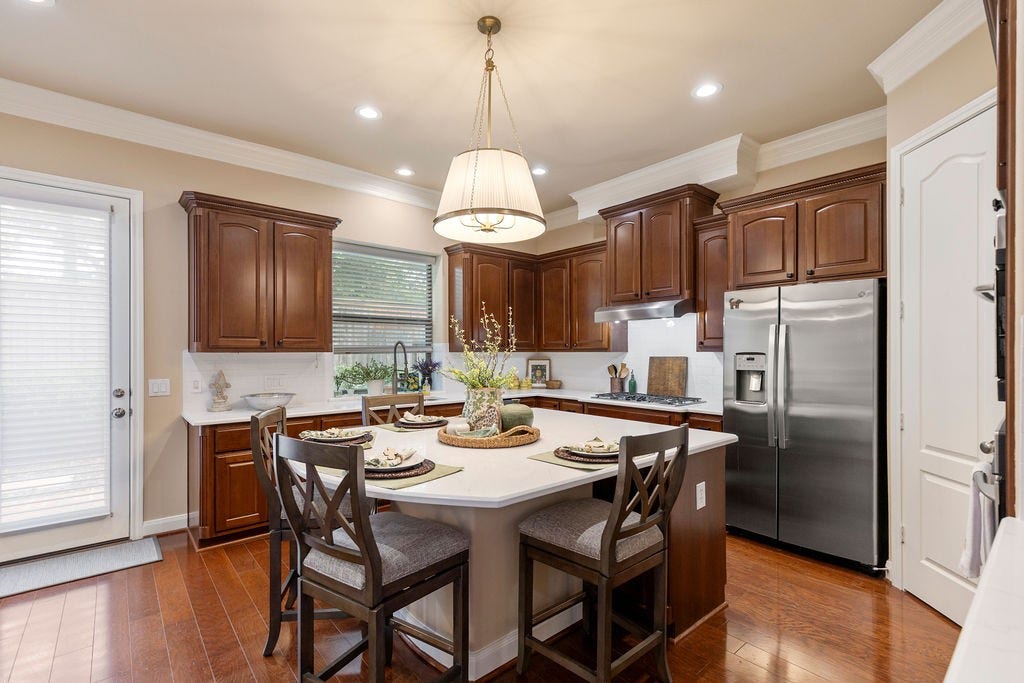 82 Mill Point Place, The Woodlands, TX 77380 The kitchen features a gas cooktop, stainless steel refrigerator, double oven, and a view out towards the backyard.