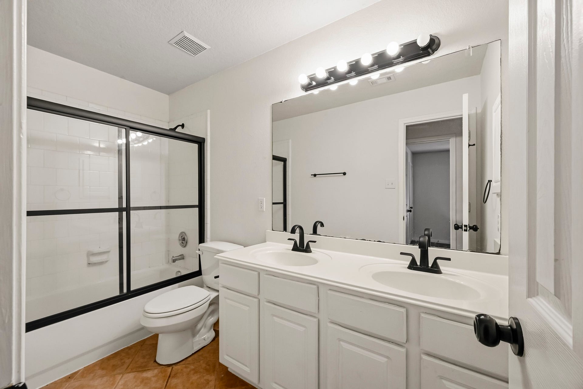 2331 Princess Deanna Lane, Katy, TX 77493 This full secondary bathroom features a double-sink vanity with plenty of lower cabinet storage and an expansive wall-to-wall vanity mirror. A full tub-and-shower combination is enclosed with sleek glass sliding doors.