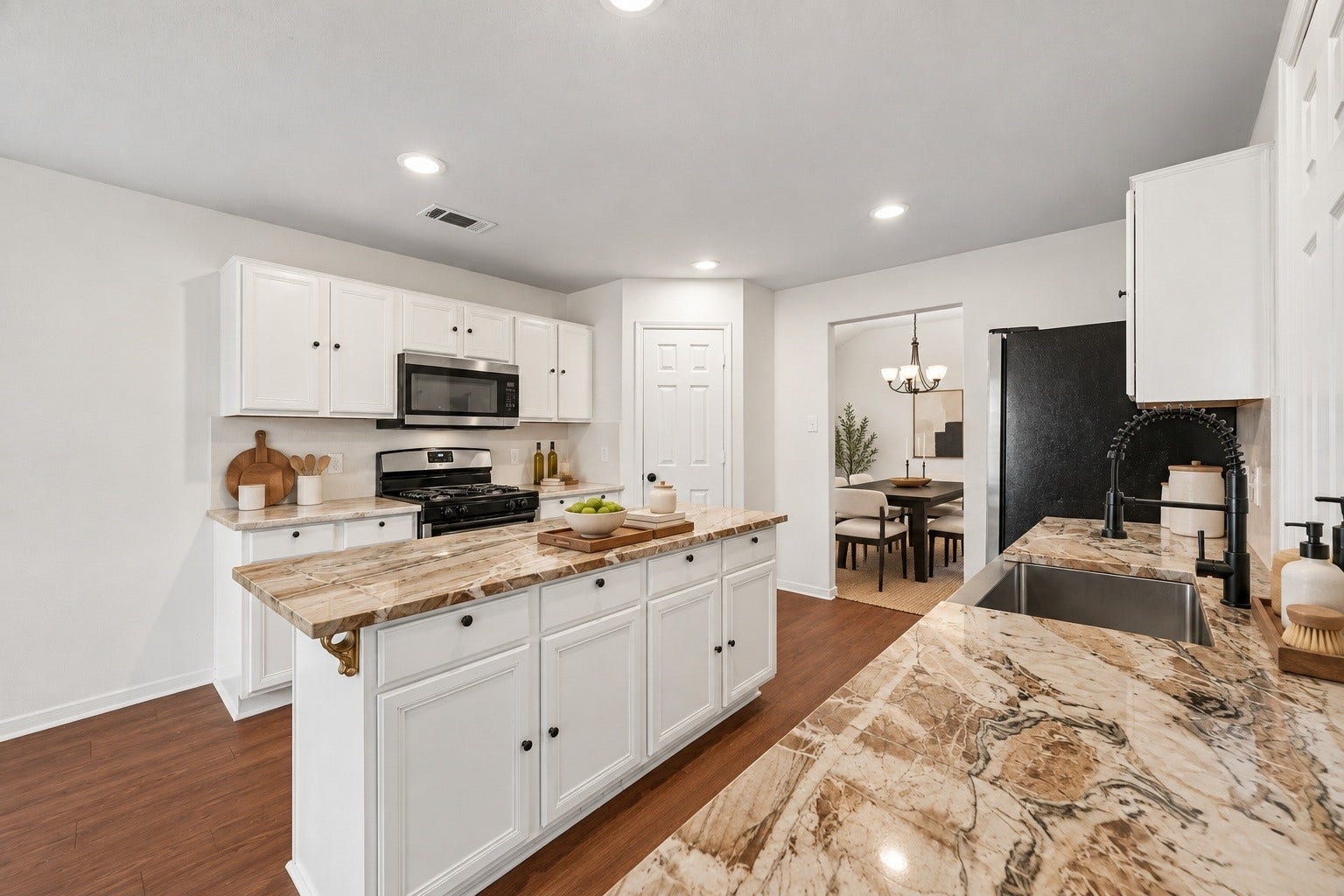 2331 Princess Deanna Lane, Katy, TX 77493 Virtually Staged: Designed with a deep sink, gooseneck faucet, built-in gas range, and microwave, the functional workspace extends into a dedicated pantry area and opens toward the adjoining dining room.
