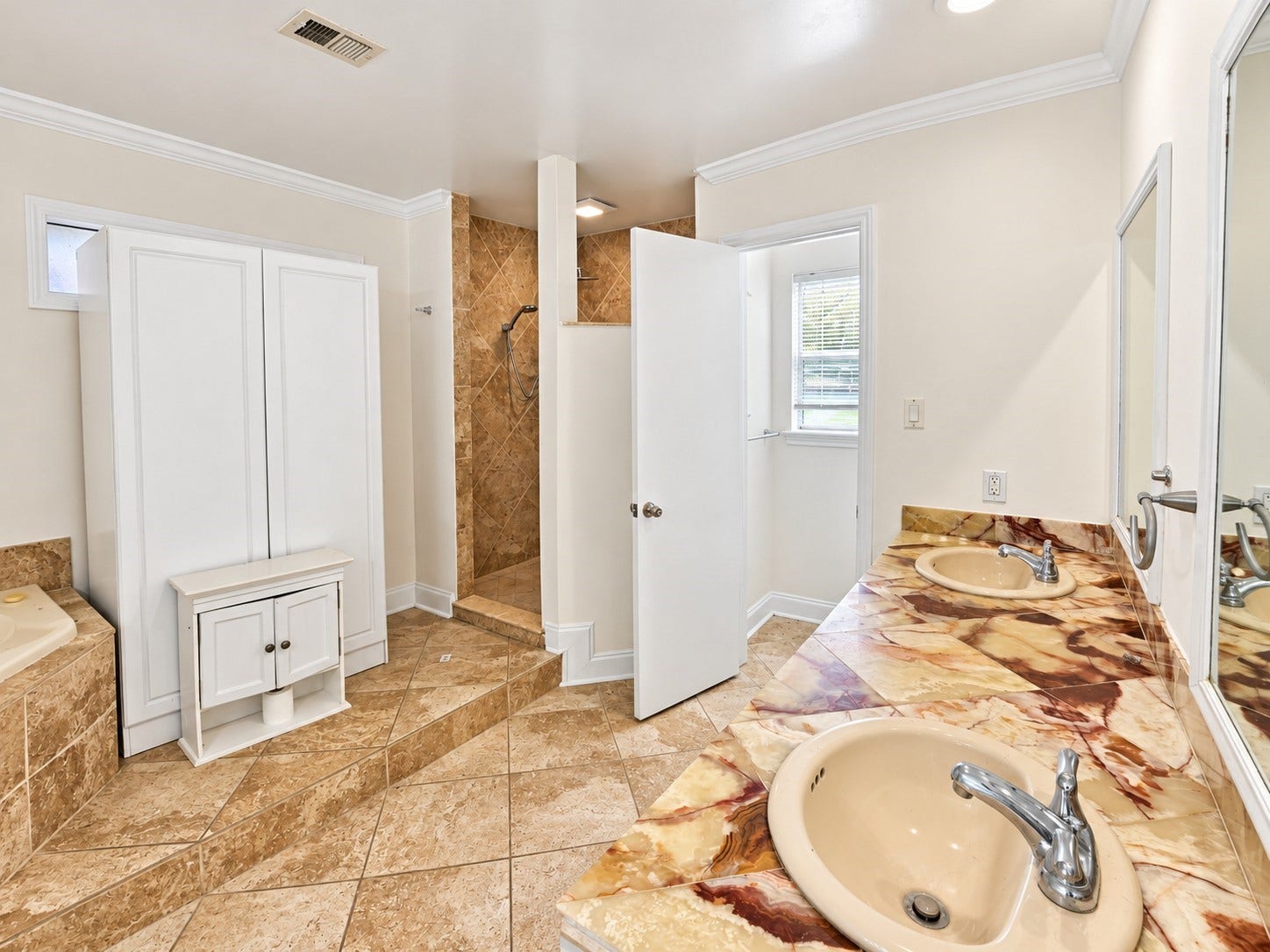 Primary en suite with double sinks, vanity area with seating, large soaking tub, and separate walk-in shower