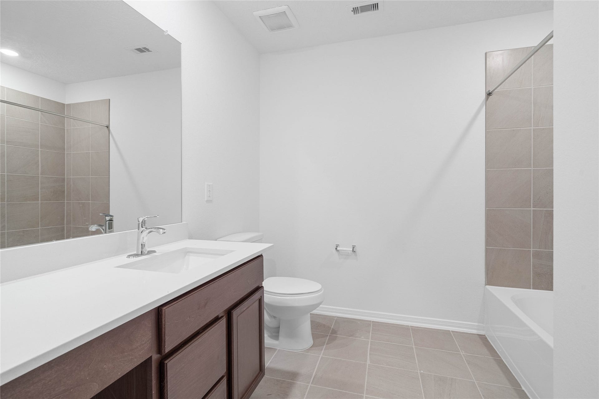 5623 Blackbird Lane, Hitchcock, TX 77563 The shared family bathroom features a rich wood vanity, crisp white countertop, and neutral tile flooring for a clean, modern look. A tiled tub and shower combination adds everyday functionality for family and guests.