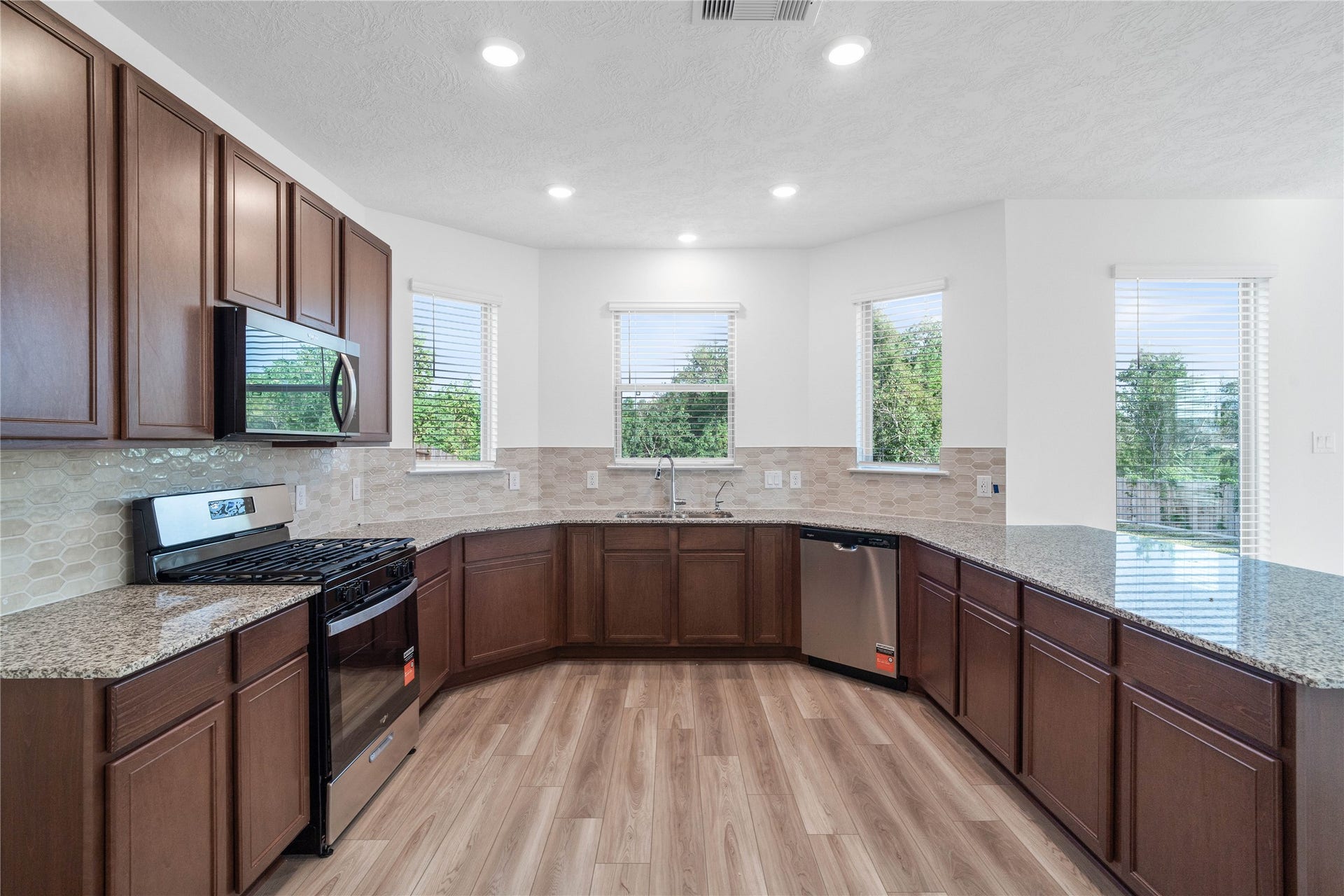 5623 Blackbird Lane, Hitchcock, TX 77563 Designed for both style and functionality, this kitchen offers abundant cabinetry, generous granite countertop space, and a convenient wraparound layout. Whirlpool appliances, a soft neutral backsplash, and warm wood look flooring complete the polished look.