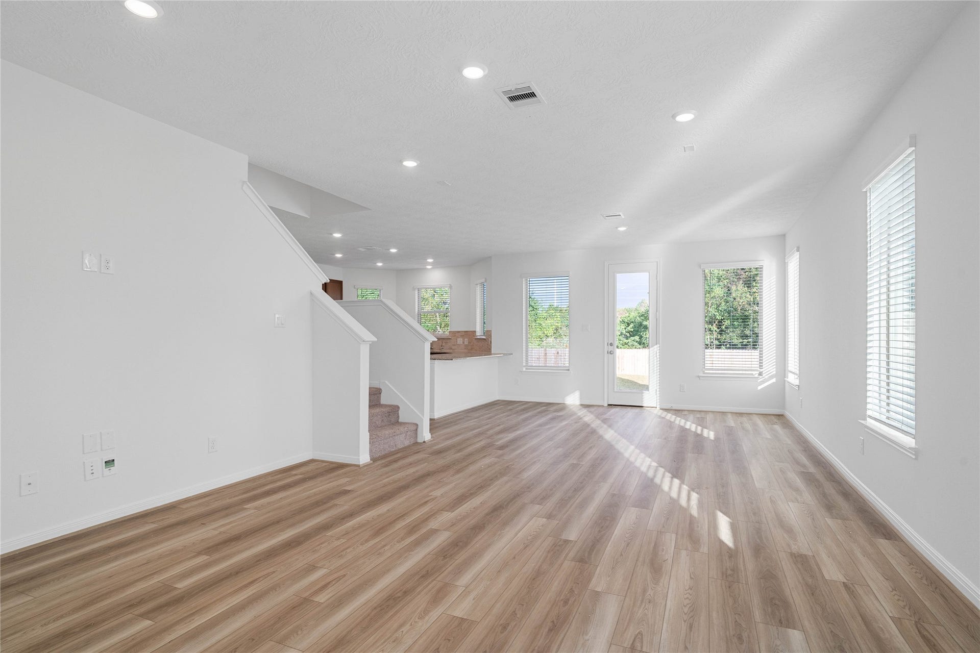 5623 Blackbird Lane, Hitchcock, TX 77563 Step inside to a bright, welcoming interior with warm wood look flooring, crisp white walls, and recessed lighting throughout. The open living space and convenient access to the staircase create a functional layout with a clean, contemporary feel.