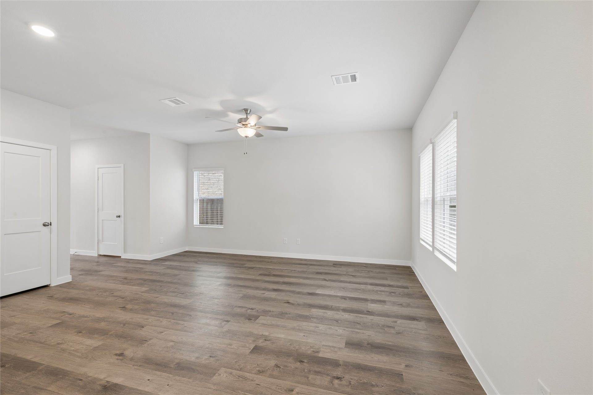 7806 Bergamot Cir, Magnolia, TX 77354 Spacious living area with elegant wood flooring, abundant natural light, and a modern ceiling fan, perfect for relaxation or entertaining.