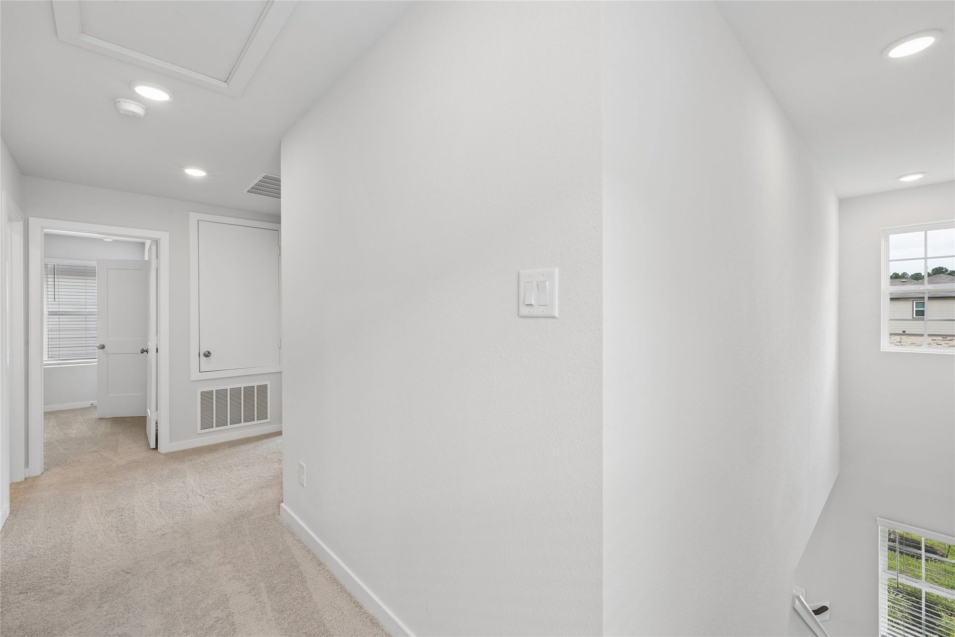 7806 Bergamot Cir, Magnolia, TX 77354 Bright and inviting hallway with plush carpeting, recessed lighting, and ample natural light from large windows, leading to a cozy room.