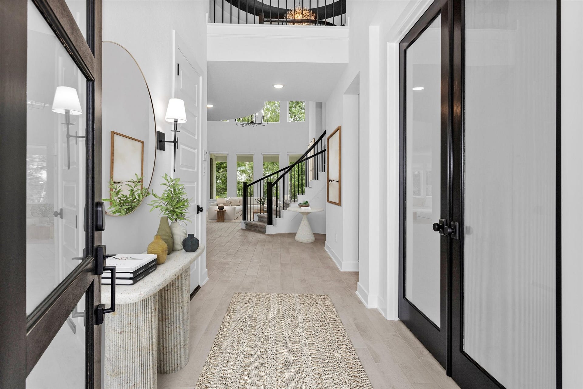 Impressive foyer featuring soaring ceilings, a dramatic spiral staircase, elegant wall sconces, and rich wood-look tile flooringcreating a grand and welcoming first impression.