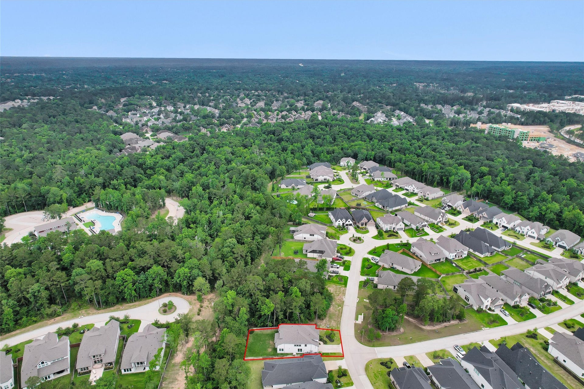This view beautifully highlights the privacy and rarity of this premium lot, showcasing lush wooded surroundings, an impressive long driveway, and a spacious backyard that is perfectly pool-ready for your future outdoor retreat. Note one of the neighborhood pools just a short walk or golf cart ride away!