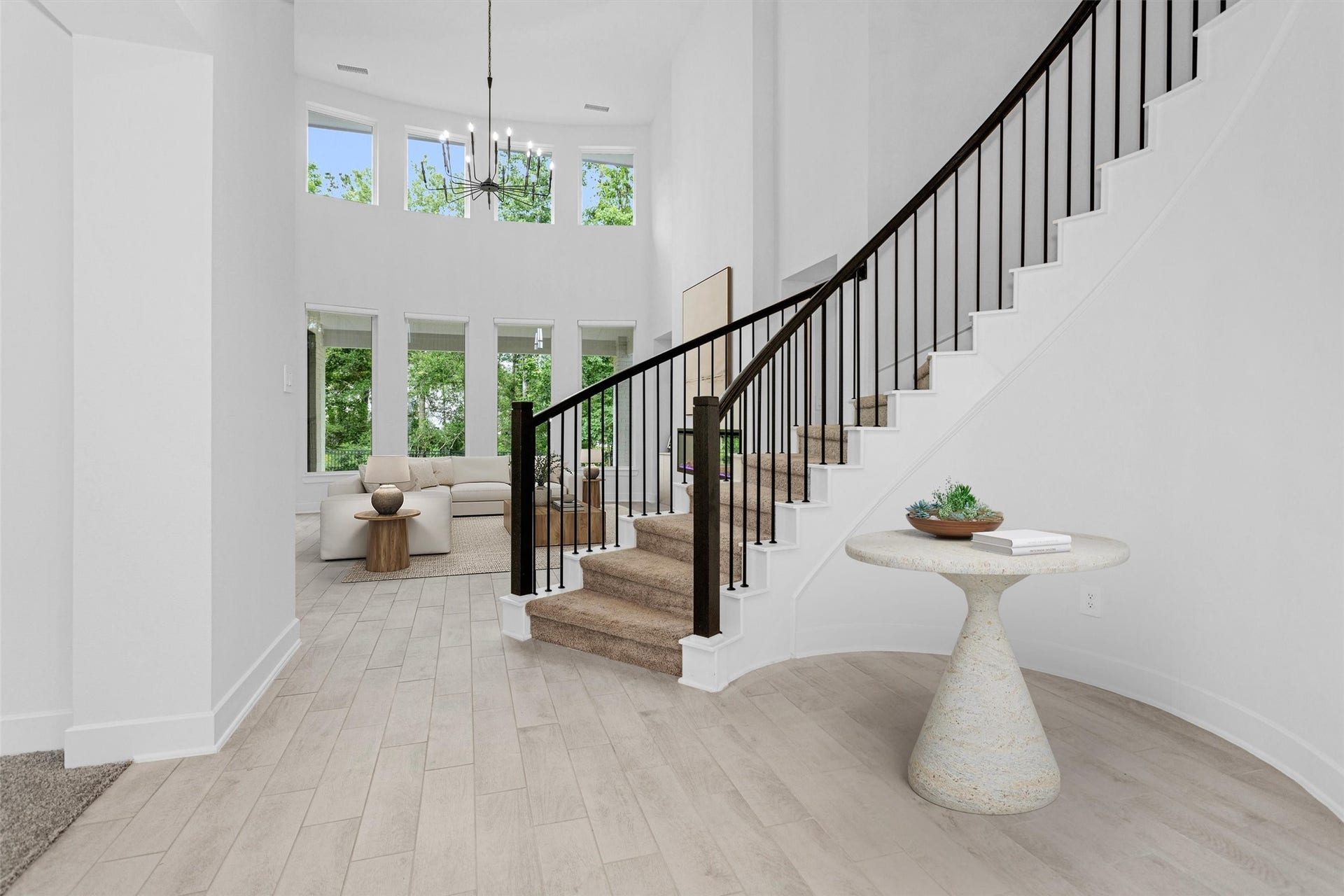 Impressive spiral staircase creates a grand and welcoming focal point, while the stunning living room showcases a dramatic wall of two-story windows framing peaceful views of the private wooded reserve and filling the home with natural light.