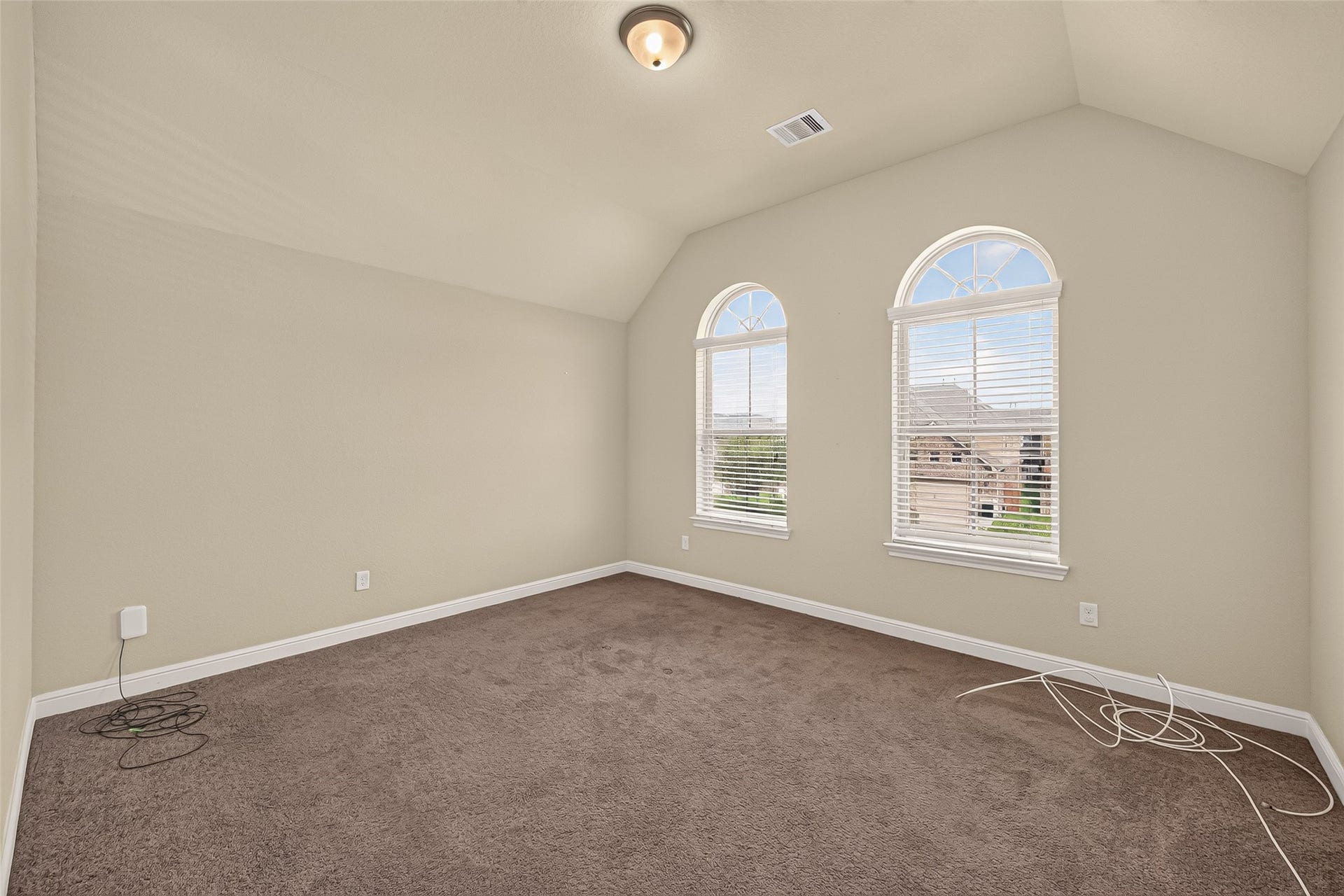 2826 Verdant Spring Trail, Katy, TX 77493 Spacious room with vaulted ceilings and charming arched windows that provide abundant natural light, ideal as a cozy retreat or sixth bedroom with an armoire.