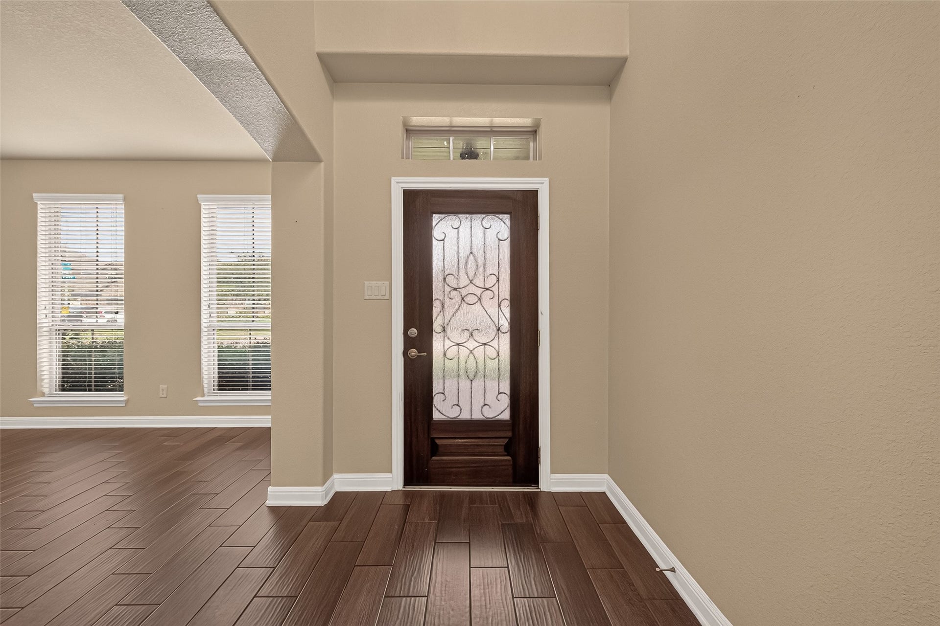 2826 Verdant Spring Trail, Katy, TX 77493 Inviting entryway with elegant wood flooring and a decorative glass front door, leading to a bright living area with ample natural light from large windows.
Elegant entryway featuring rich wood-look tile flooring and graceful archways, leading to a charming staircase with decorative iron balusters.