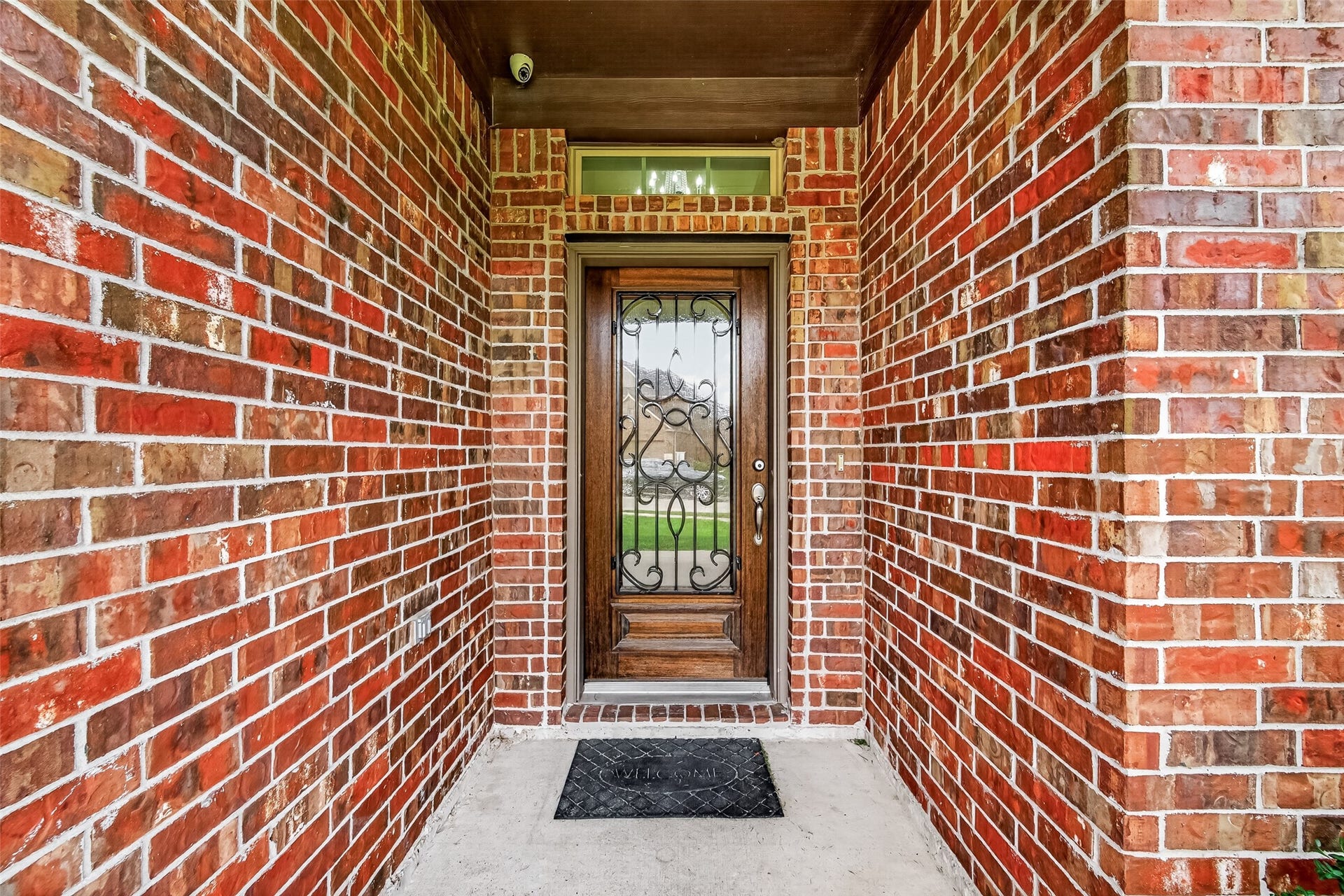 2826 Verdant Spring Trail, Katy, TX 77493 Inviting entrance with a charming wooden door featuring ornate ironwork, set against classic red brick walls.