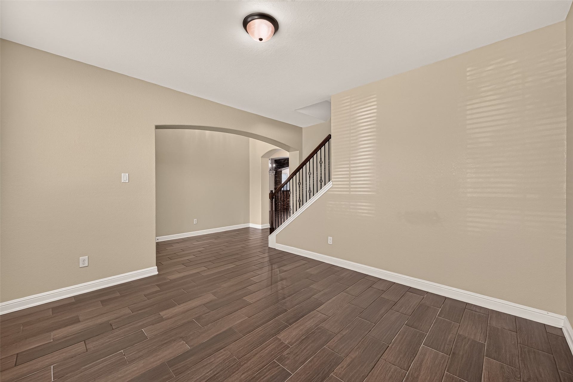 2826 Verdant Spring Trail, Katy, TX 77493 Spacious Office area with elegant wood-look tile flooring and a graceful archway leading to the staircase, creating a warm and inviting ambiance.