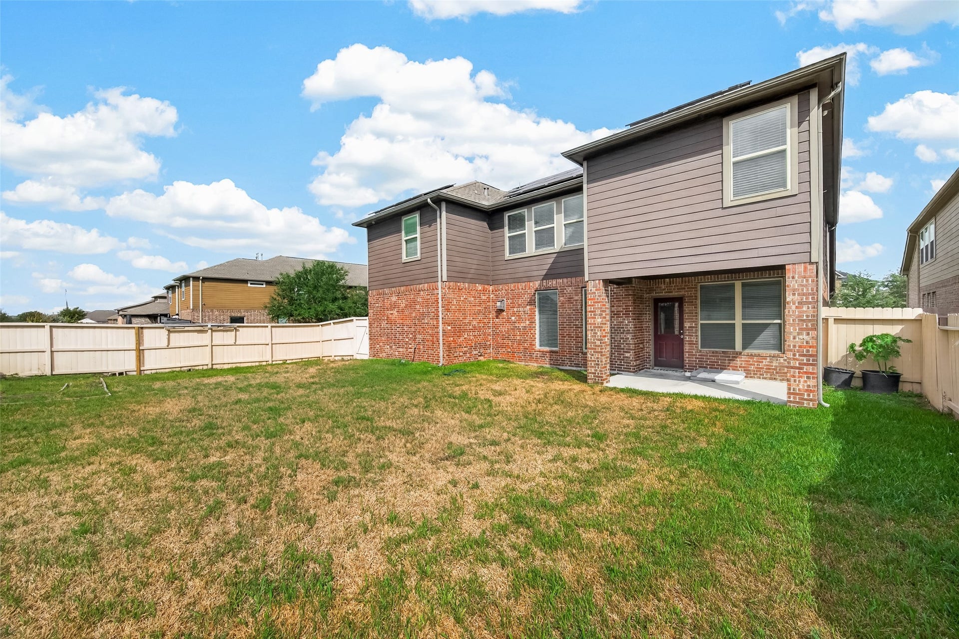 2826 Verdant Spring Trail, Katy, TX 77493 Spacious backyard with lush grass, perfect for outdoor activities, complemented by a two-story brick and siding home offering ample natural light and privacy with a fenced perimeter.