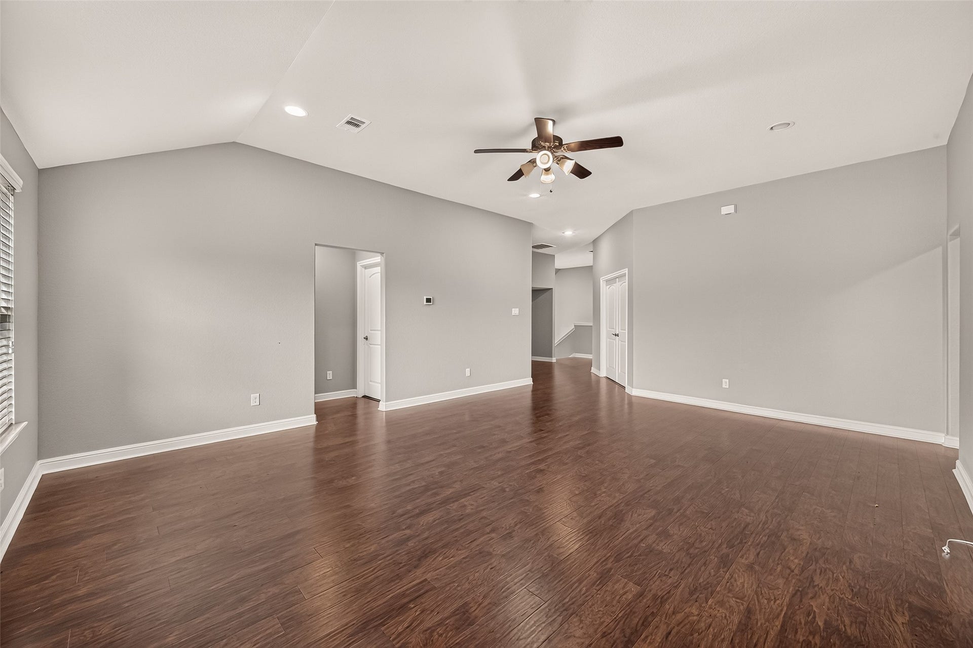 2826 Verdant Spring Trail, Katy, TX 77493 Spacious Game room area with elegant hardwood floors, ample natural light from large windows, and a modern ceiling fan, perfect for family gatherings.