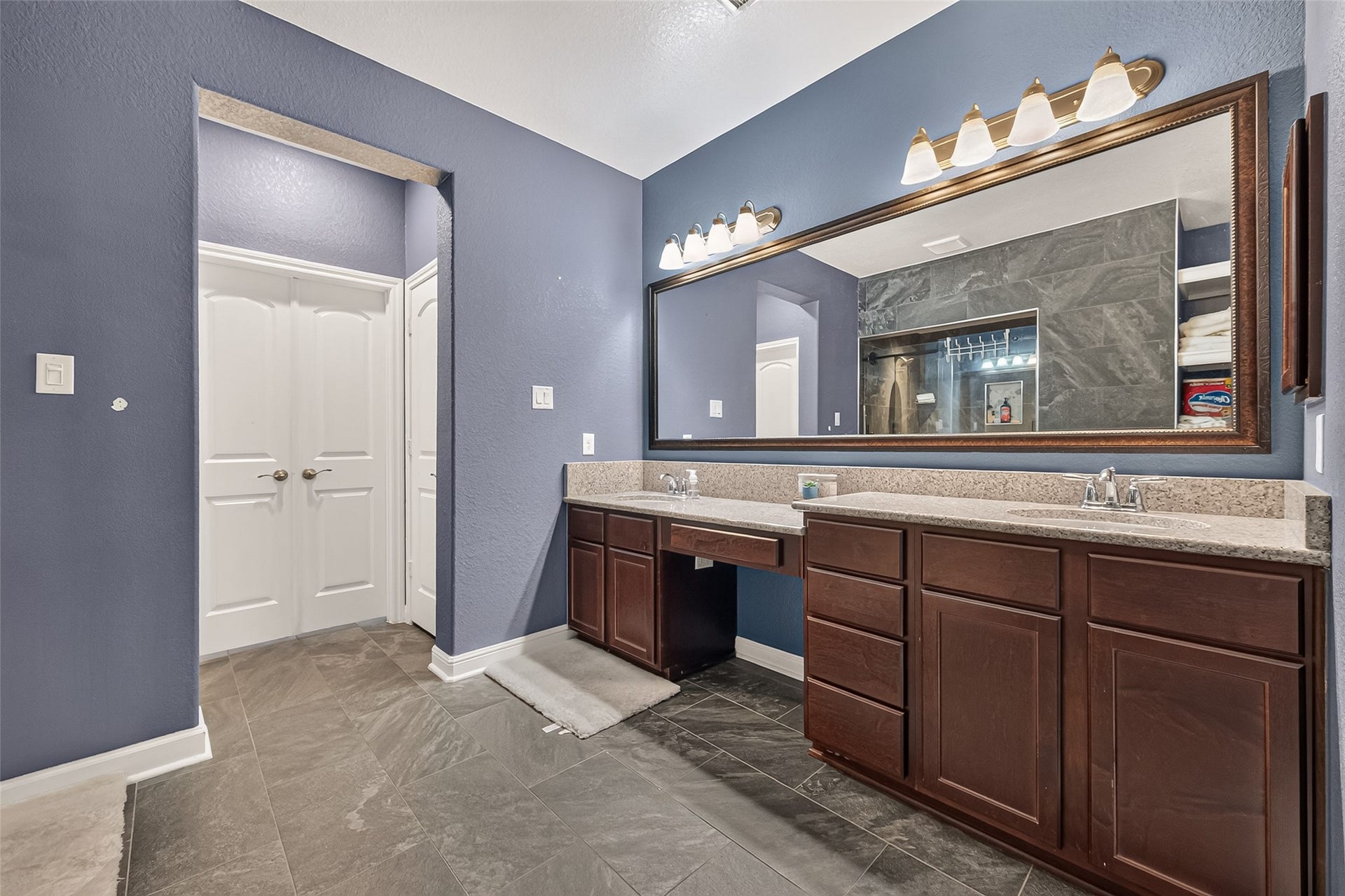2826 Verdant Spring Trail, Katy, TX 77493 Refined primary bathroom showcasing dual vanities, finely crafted wood cabinetry, generous countertops, an oversized framed mirror, sophisticated lighting, and polished tile flooring.