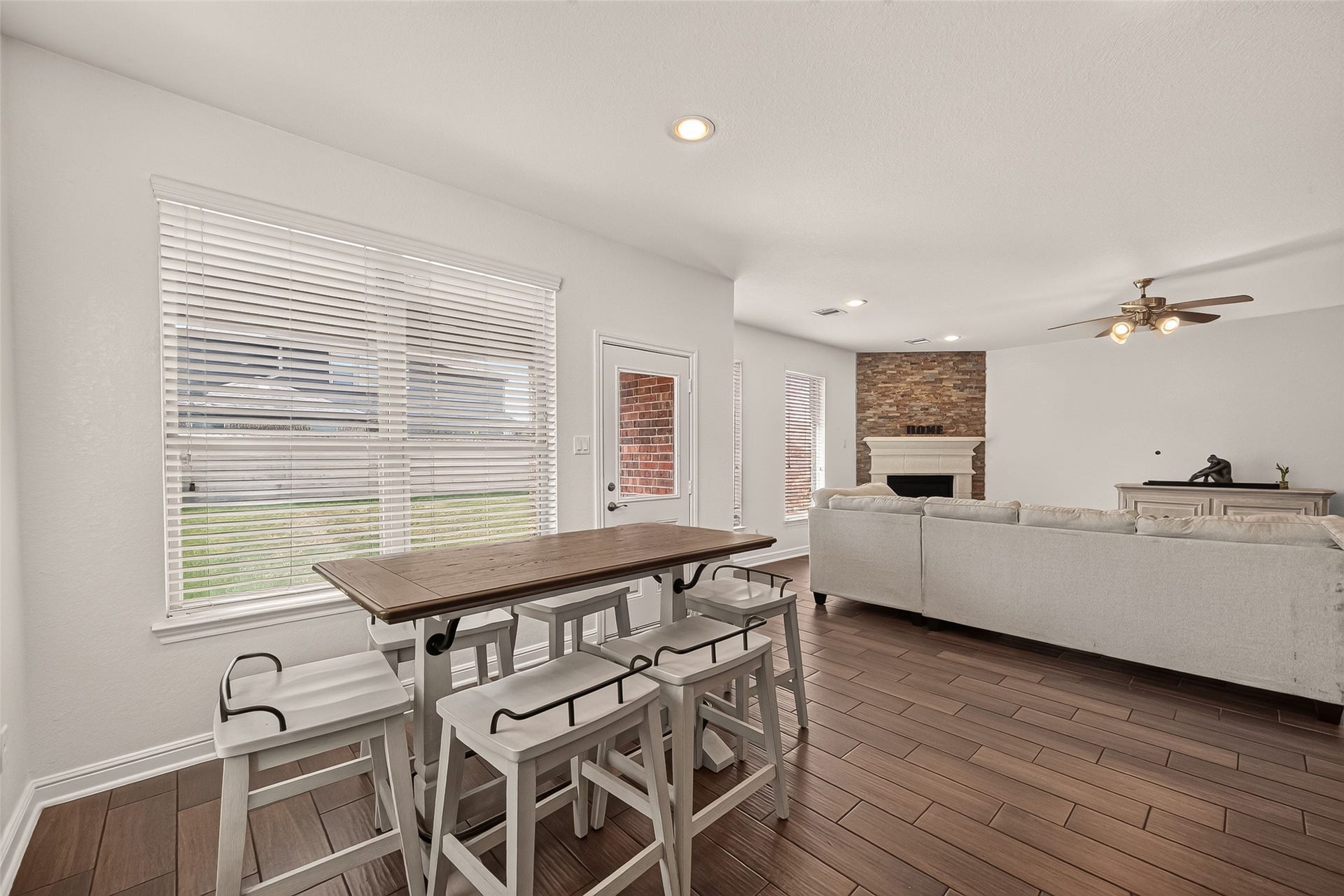 2826 Verdant Spring Trail, Katy, TX 77493 Spacious breakfast room opening to the living area, with elegant wood-look ceramic tile flooring, a cozy stone fireplace, and large windows that fill the space with natural light.