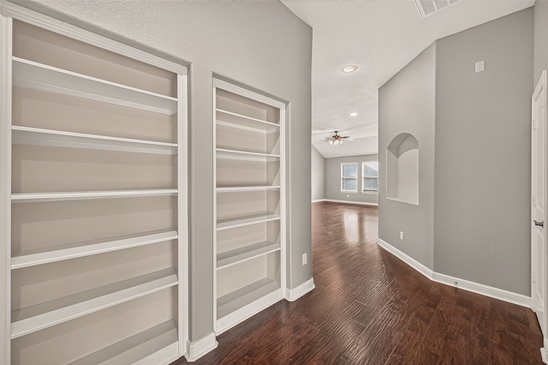 2826 Verdant Spring Trail, Katy, TX 77493 Elegant hallway with built-in shelving leads to a spacious living area, featuring rich hardwood floors, neutral walls, and abundant natural light.