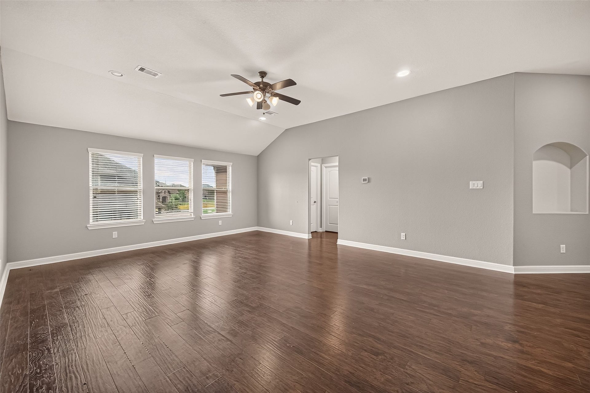 2826 Verdant Spring Trail, Katy, TX 77493 Spacious Gameroom with elegant hardwood floors, ample natural light from large windows, and a modern ceiling fan, perfect for family gatherings.