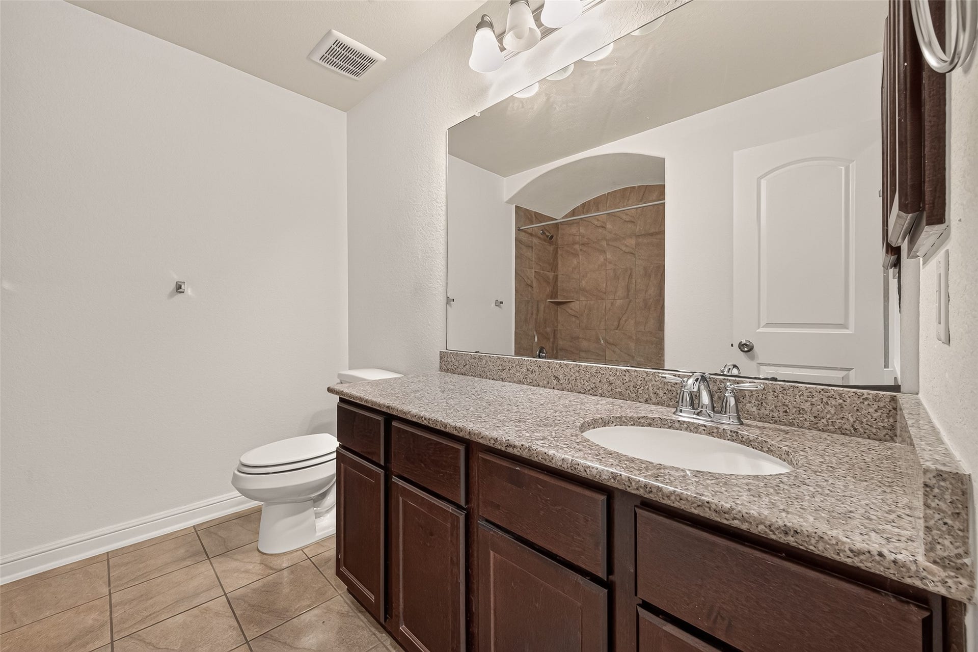 2826 Verdant Spring Trail, Katy, TX 77493 Spacious secondary bathroom featuring an expansive granite vanity with a porcelain sink, rich dark-wood cabinetry, and a stylish tiled shower.