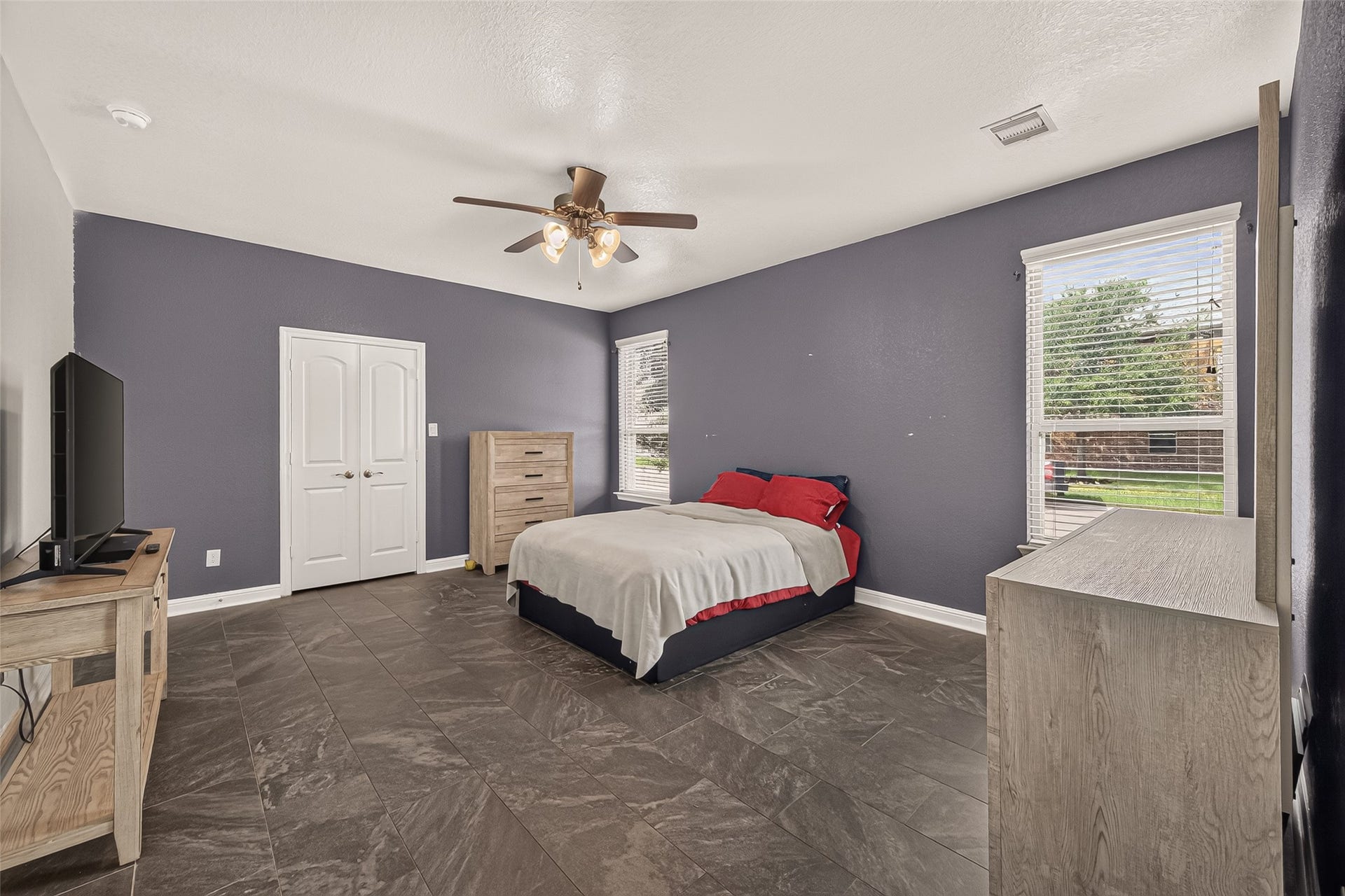 2826 Verdant Spring Trail, Katy, TX 77493 Luxurious primary suite showcasing sleek tile flooring, a contemporary ceiling fan, and expansive windows that bathe the space in natural light, creating a serene private retreat.