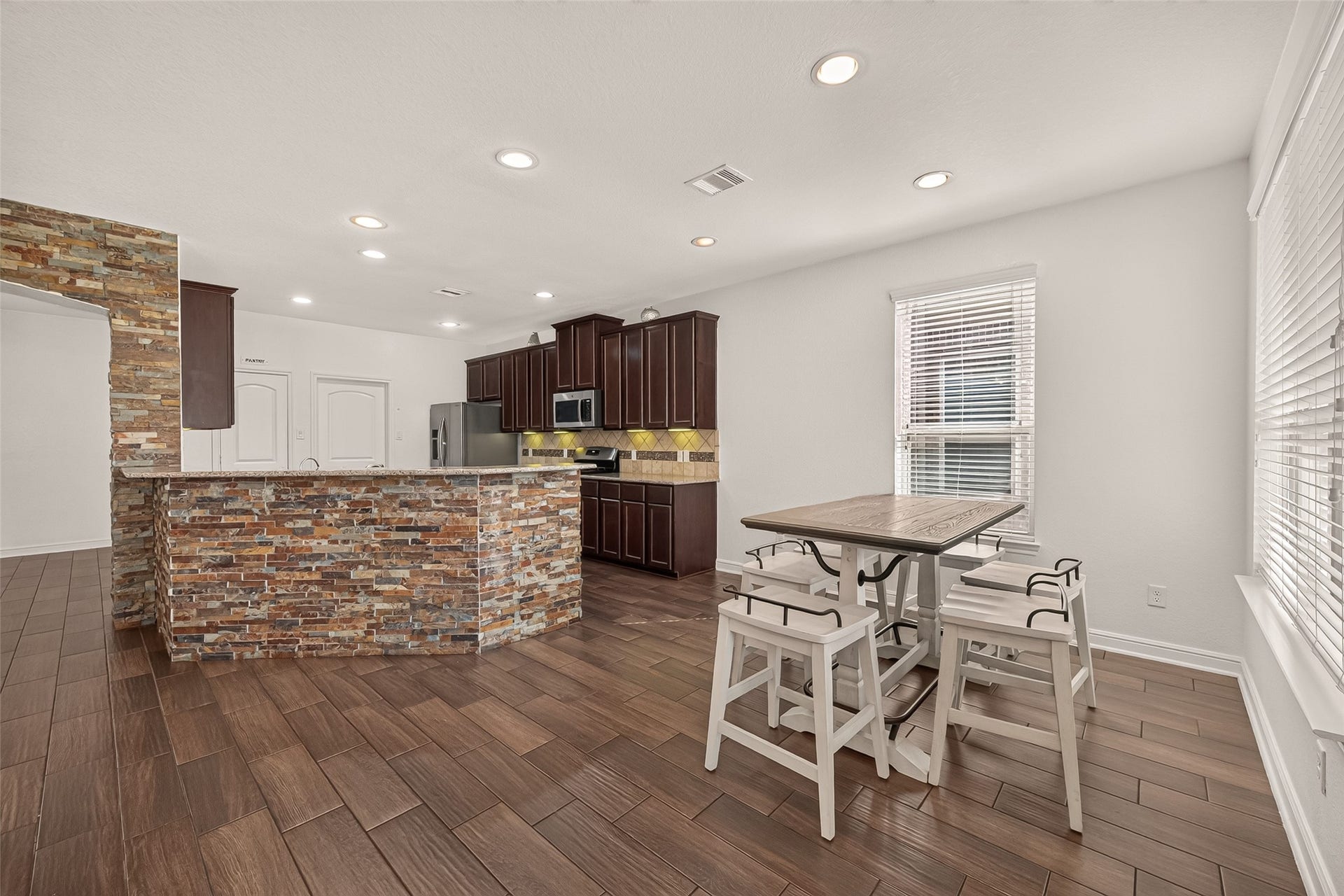 2826 Verdant Spring Trail, Katy, TX 77493 Spacious kitchen and breakfast area with rich dark-wood cabinetry, a stylish stone accent wall, and a cozy, light-filled dining nook.