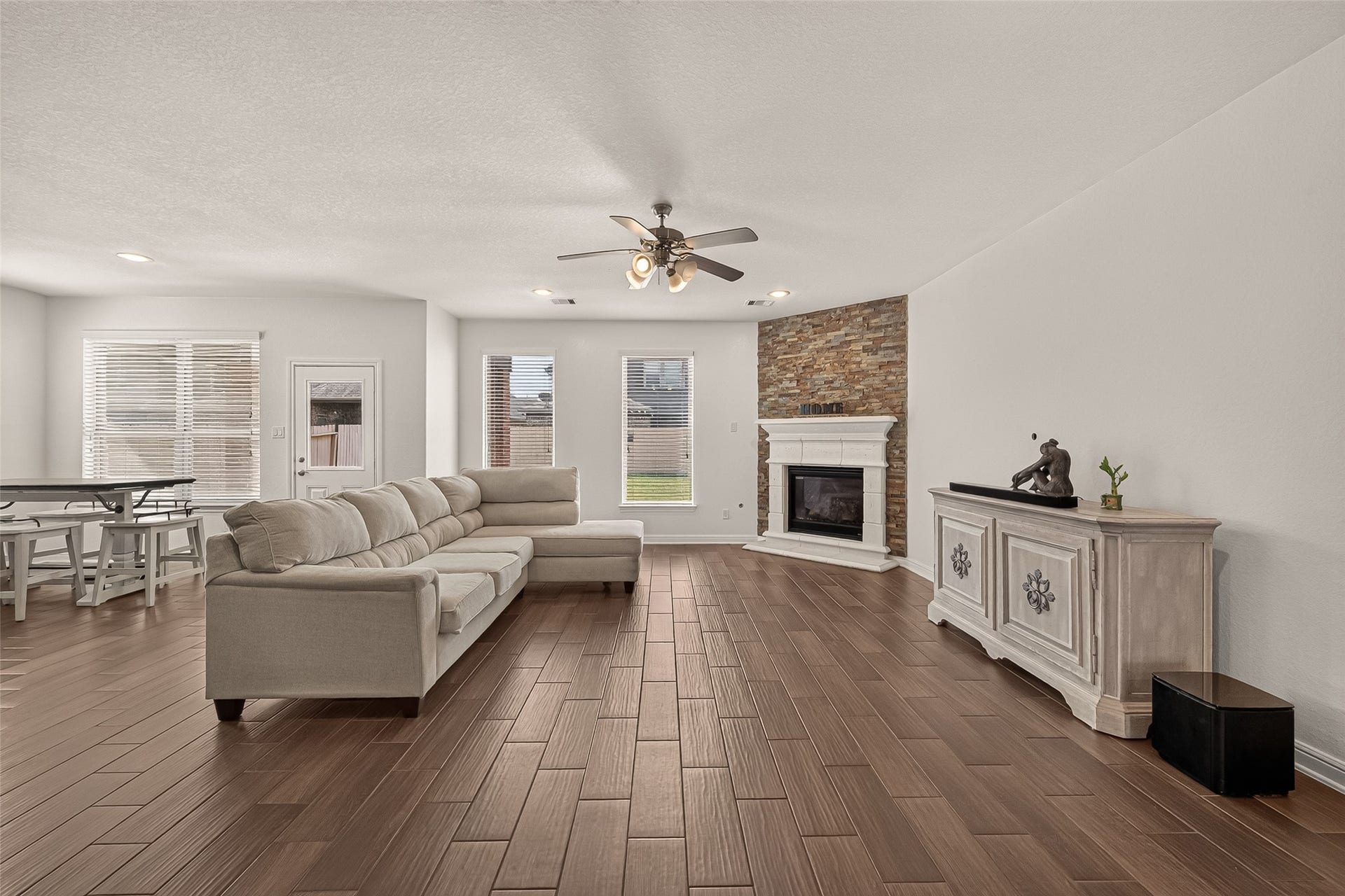 2826 Verdant Spring Trail, Katy, TX 77493 Spacious living area featuring a cozy stone fireplace, elegant wood-look flooring, and abundant natural light from large windows.