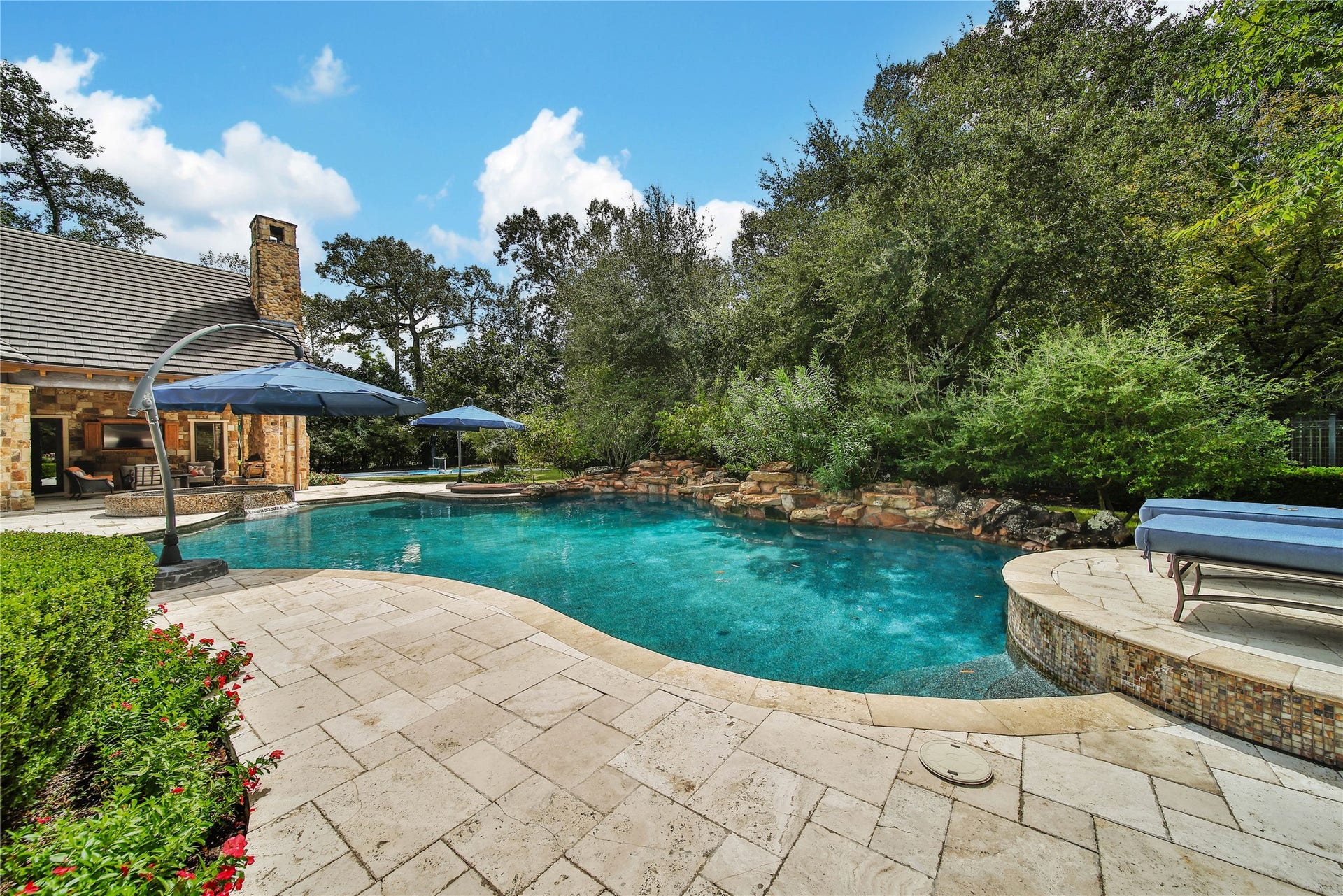 247 S Fazio Way, Spring, TX 77389 Designed for effortless entertaining, this remarkable backyard retreat features an impressive travertine patio, elevated spa, custom pool, and multiple lounge areas, all within a serene wooded setting that creates a true outdoor sanctuary.