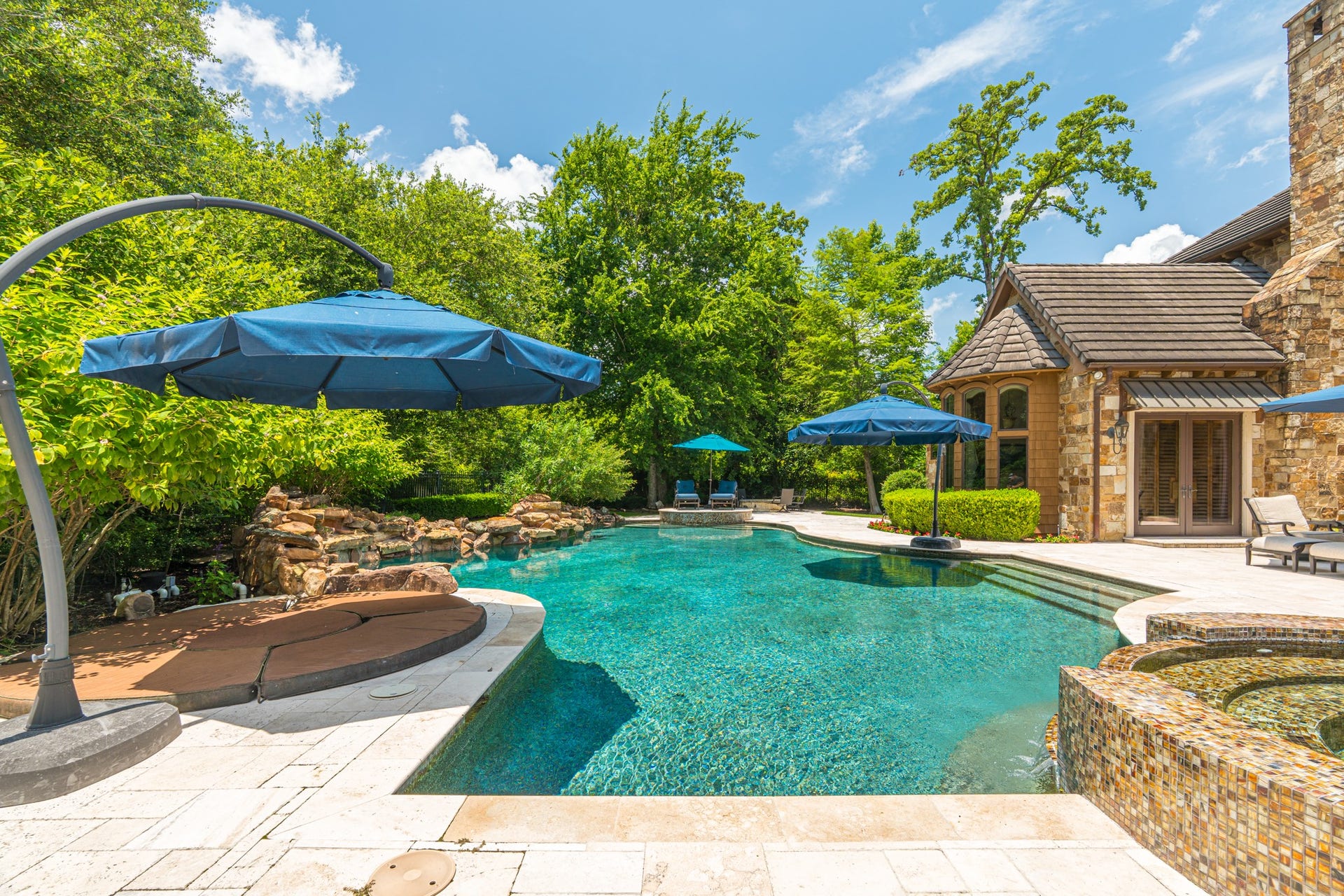 247 S Fazio Way, Spring, TX 77389 Resort-style living comes to life with a stunning pool and spa, sun shelf seating, water features, and multiple lounging areas surrounded by lush mature landscaping providing secluded atmosphere.