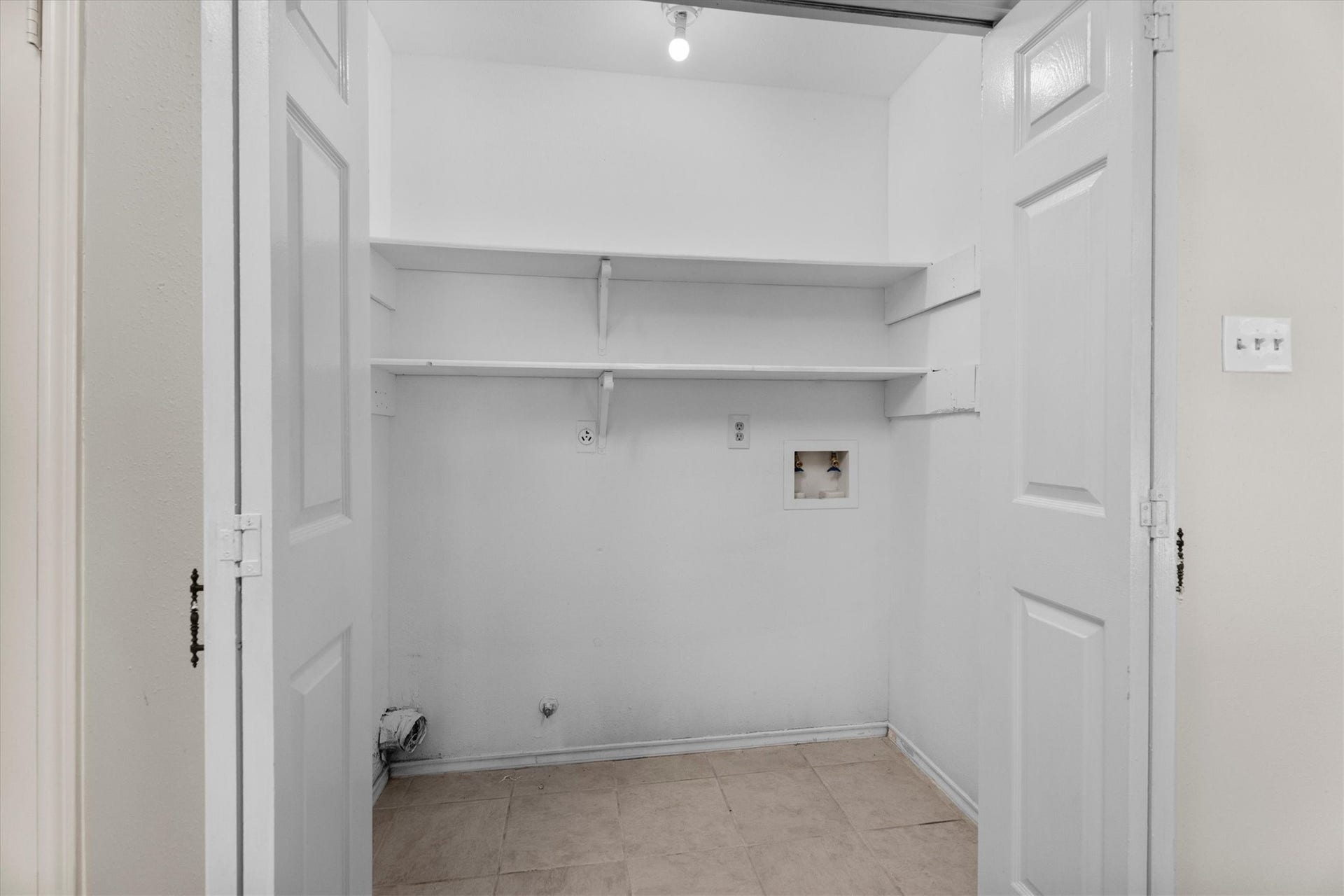 Interior utility area with built-in shelving, washer and dryer connections.