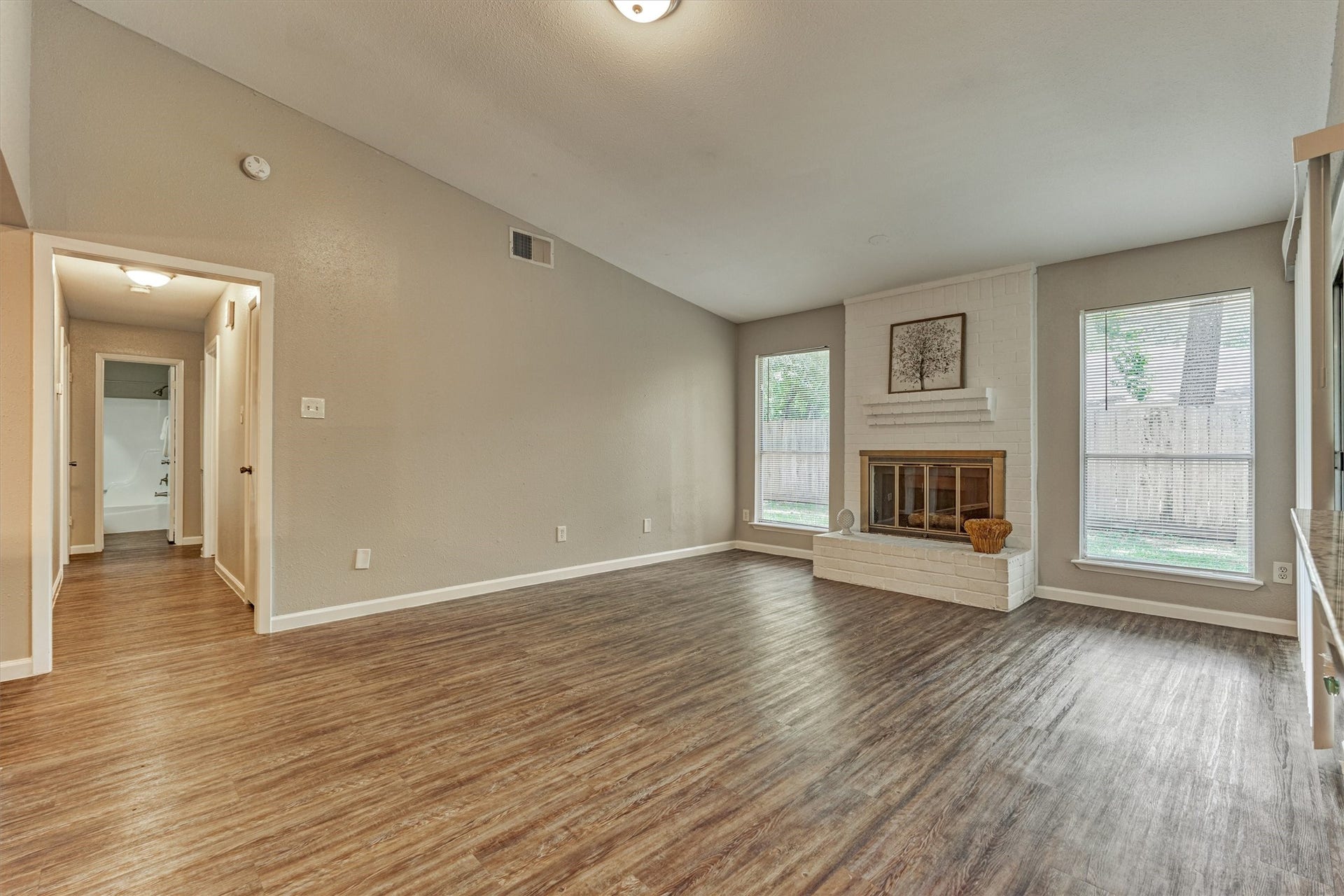 26 W Broken Oak Court, The Woodlands, TX 77381 In the living area, large windows flank the gas fireplace and allow natural light into the space.