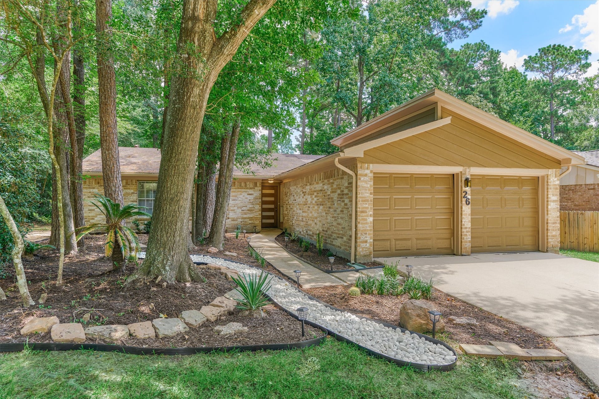 26 W Broken Oak Court, The Woodlands, TX 77381 Low maintenance landscaping is achieved with a dry creek, mature trees and climate zone appropriate plantings.