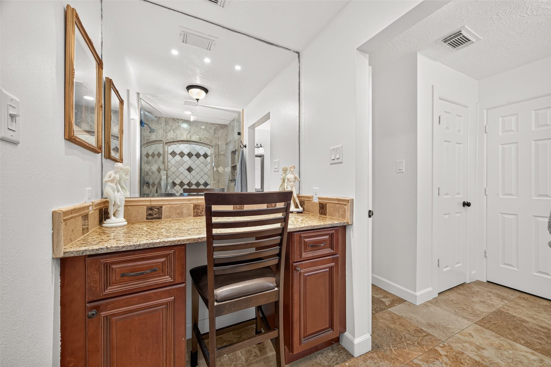 Dedicated vanity area in the primary en-suite features granite countertops, built-in cabinetry and an oversized mirror.