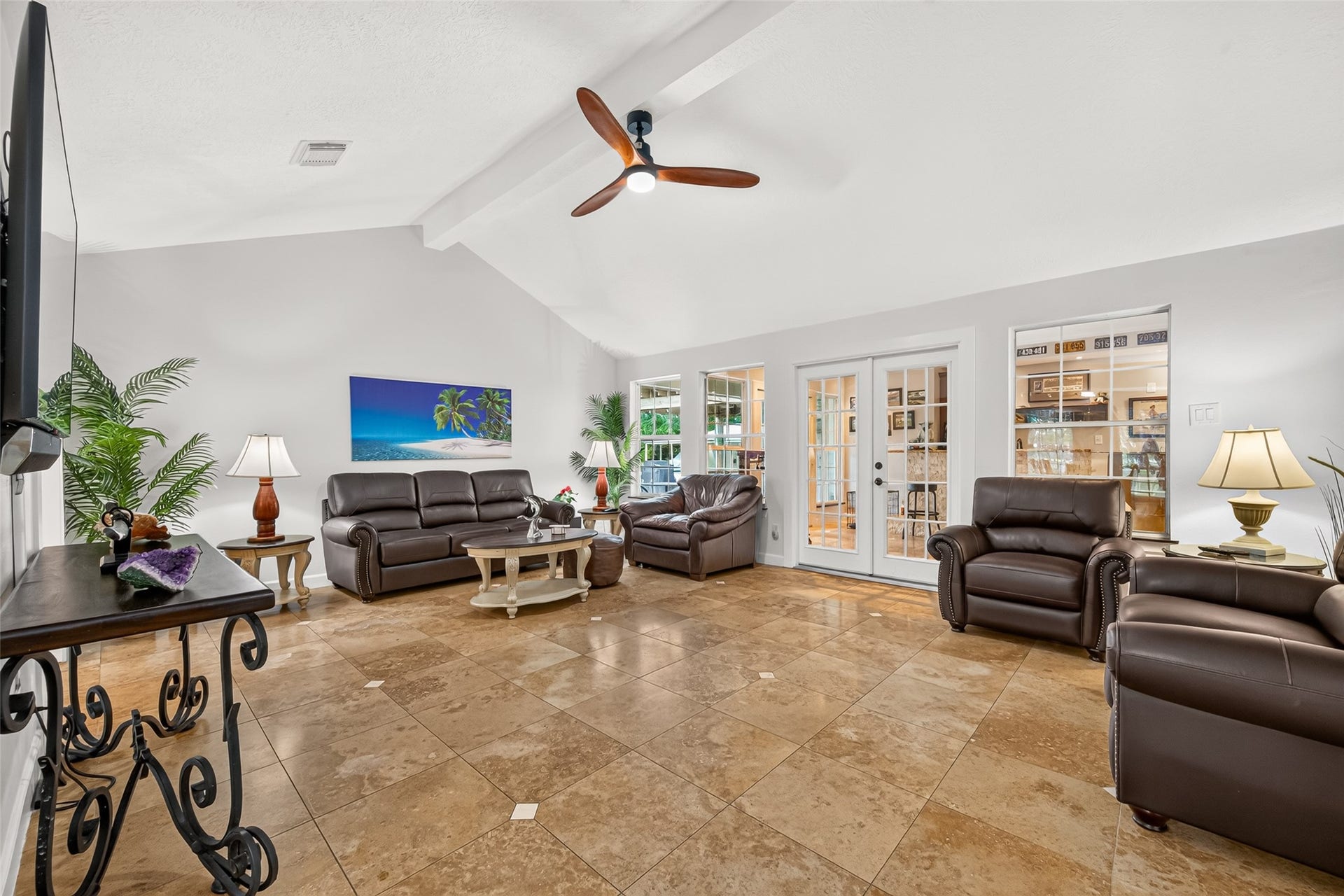Spacious main living area with vaulted ceilings, tile flooring and French doors leading into the game room.