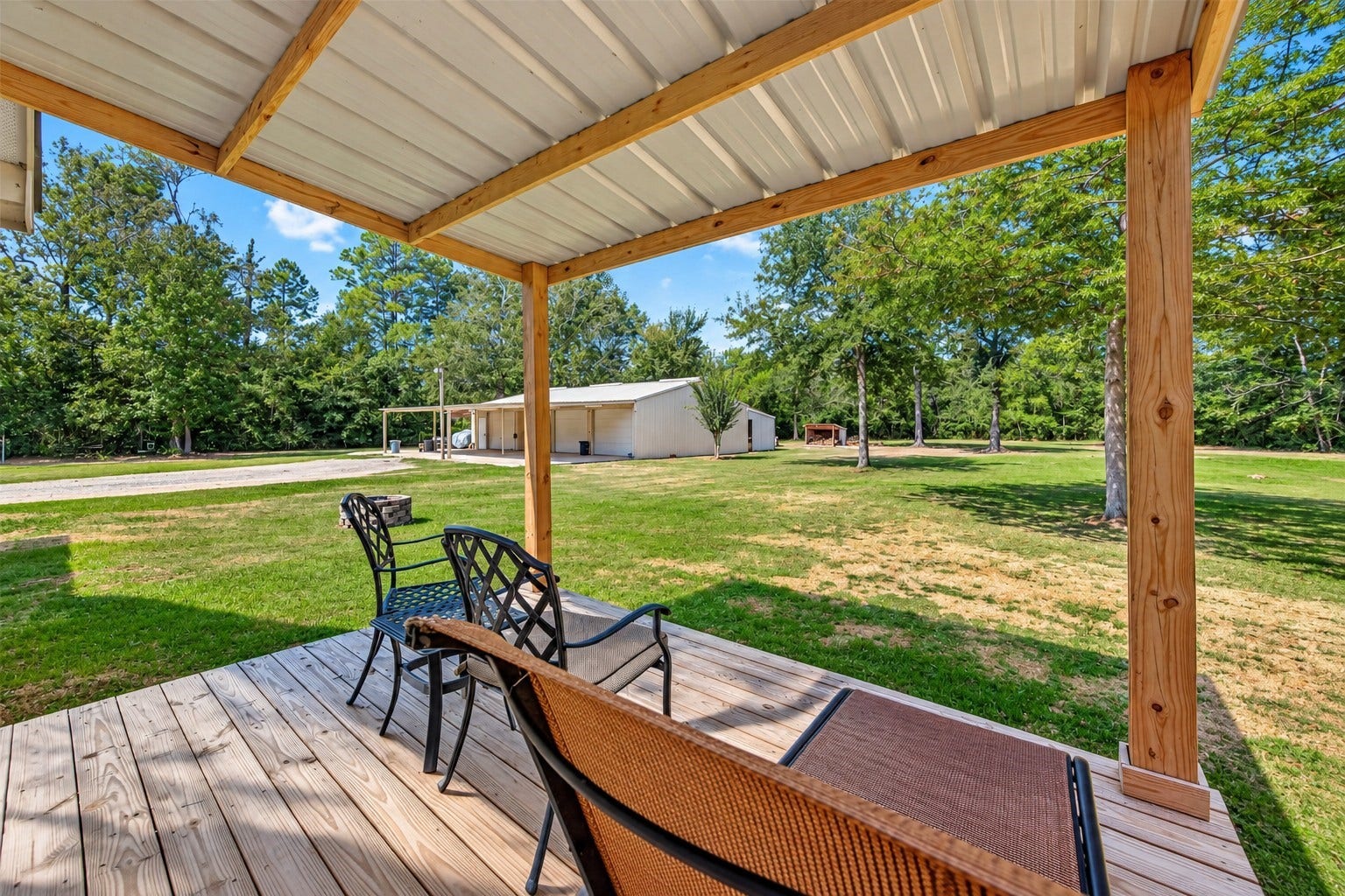 Covered back deck overlooking the spacious property with a view of the large workshop.