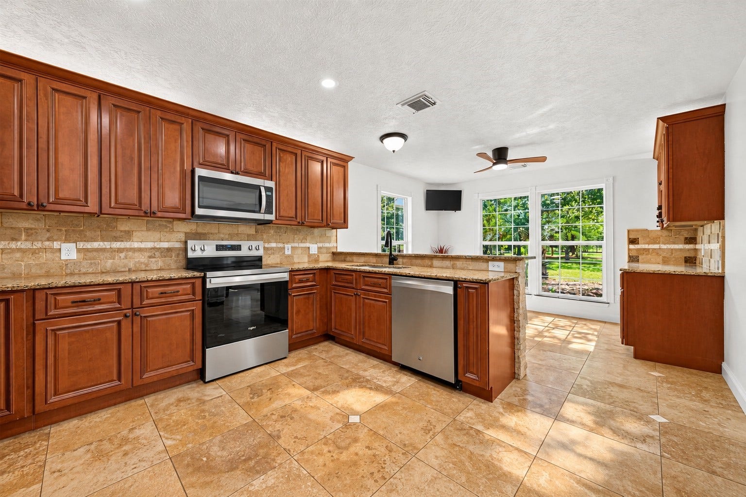 Spacious kitchen with abundant cabinetry, granite countertops, stainless steel appliances and an open layout overlooking the breakfast area.