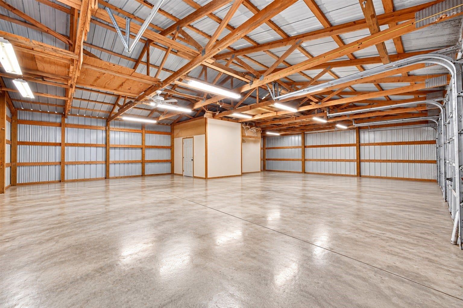 Impressive interior of the 4-car bay shop featuring finished concrete flooring, abundant overhead lighting and expansive open space for vehicles, equipment, storage and projects.