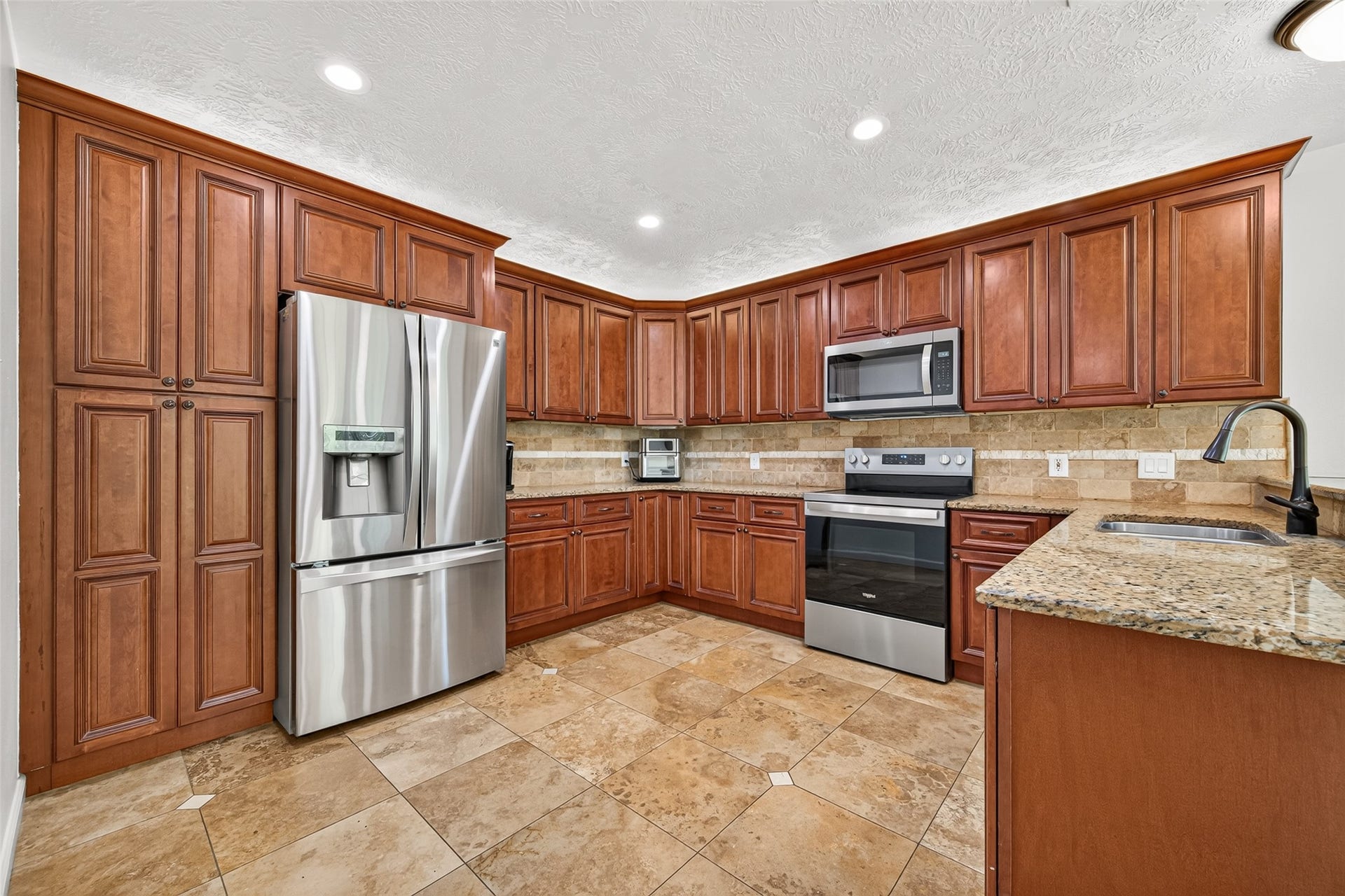 Well-appointed kitchen with granite countertops, stainless steel appliances, tile backsplash and an abundance of cabinetry for storage.