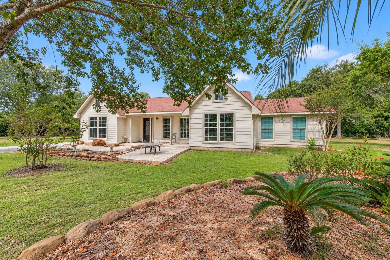 Closer view of the home showcasing the mature landscaping, established trees and inviting front entry.