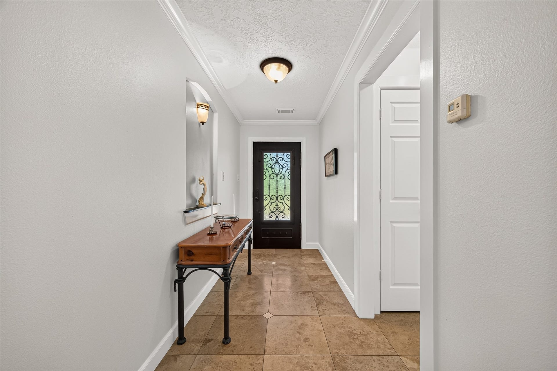 View back toward the front entry, highlighting the tiled foyer and decorative iron-and-glass front door.