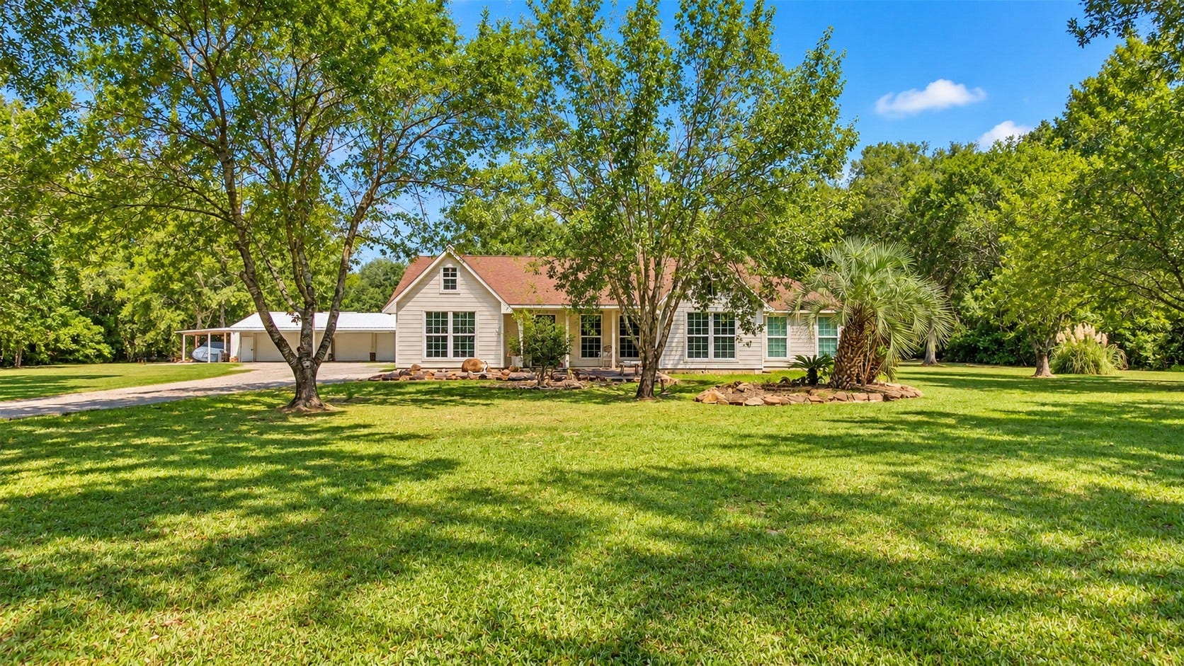 Beautiful front view showcasing the home surrounded by mature trees, expansive lawn, and plenty of privacy.