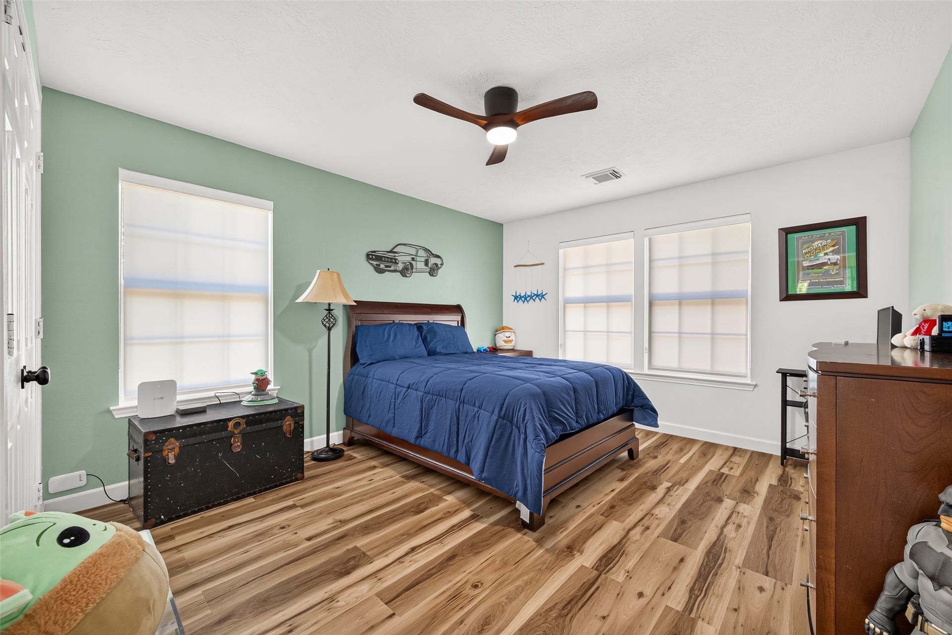 Spacious secondary bedroom with multiple windows, wood-look flooring and plenty of natural light.