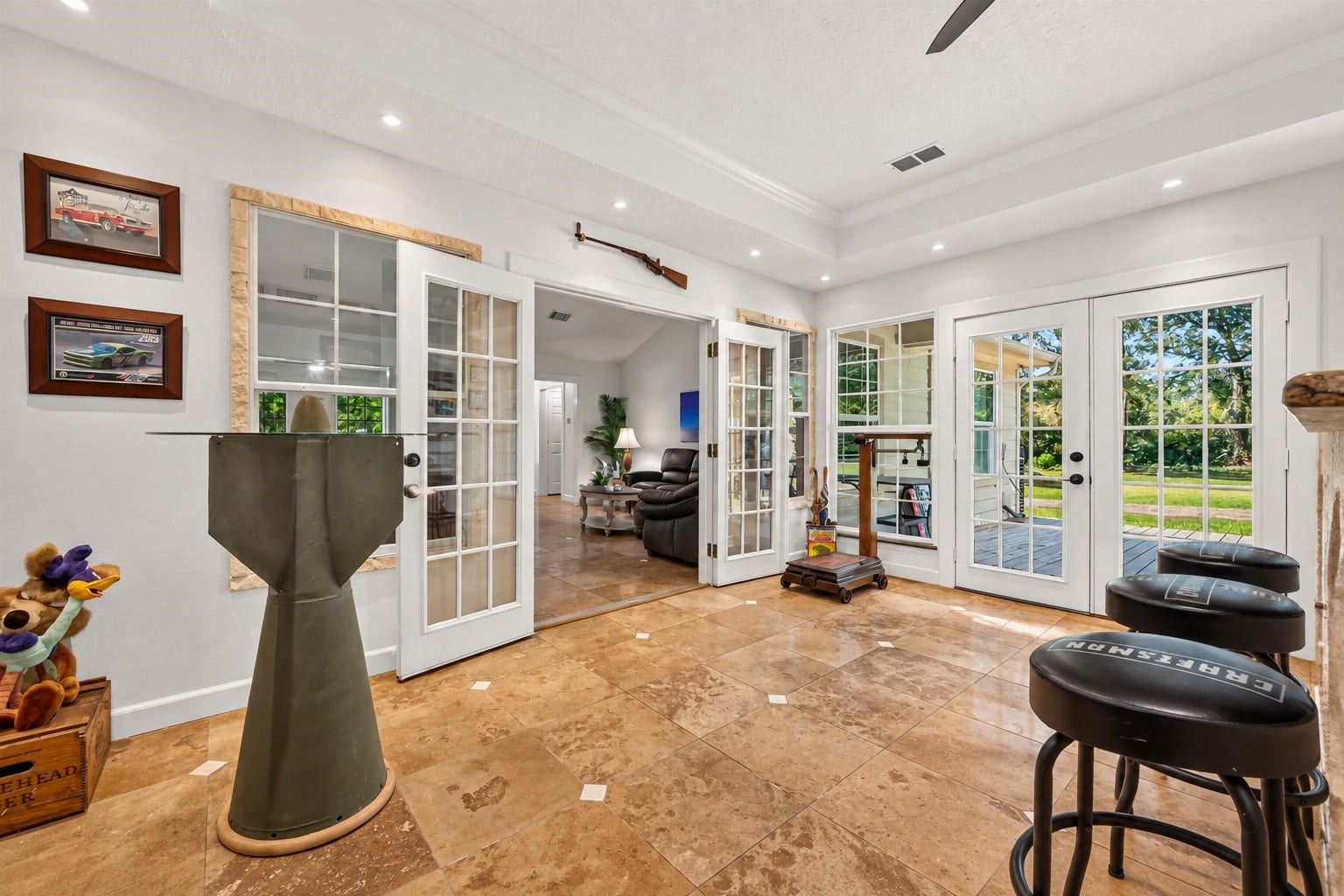 Game room with French doors opening to the main living area and additional French doors providing direct access to the covered outdoor space.