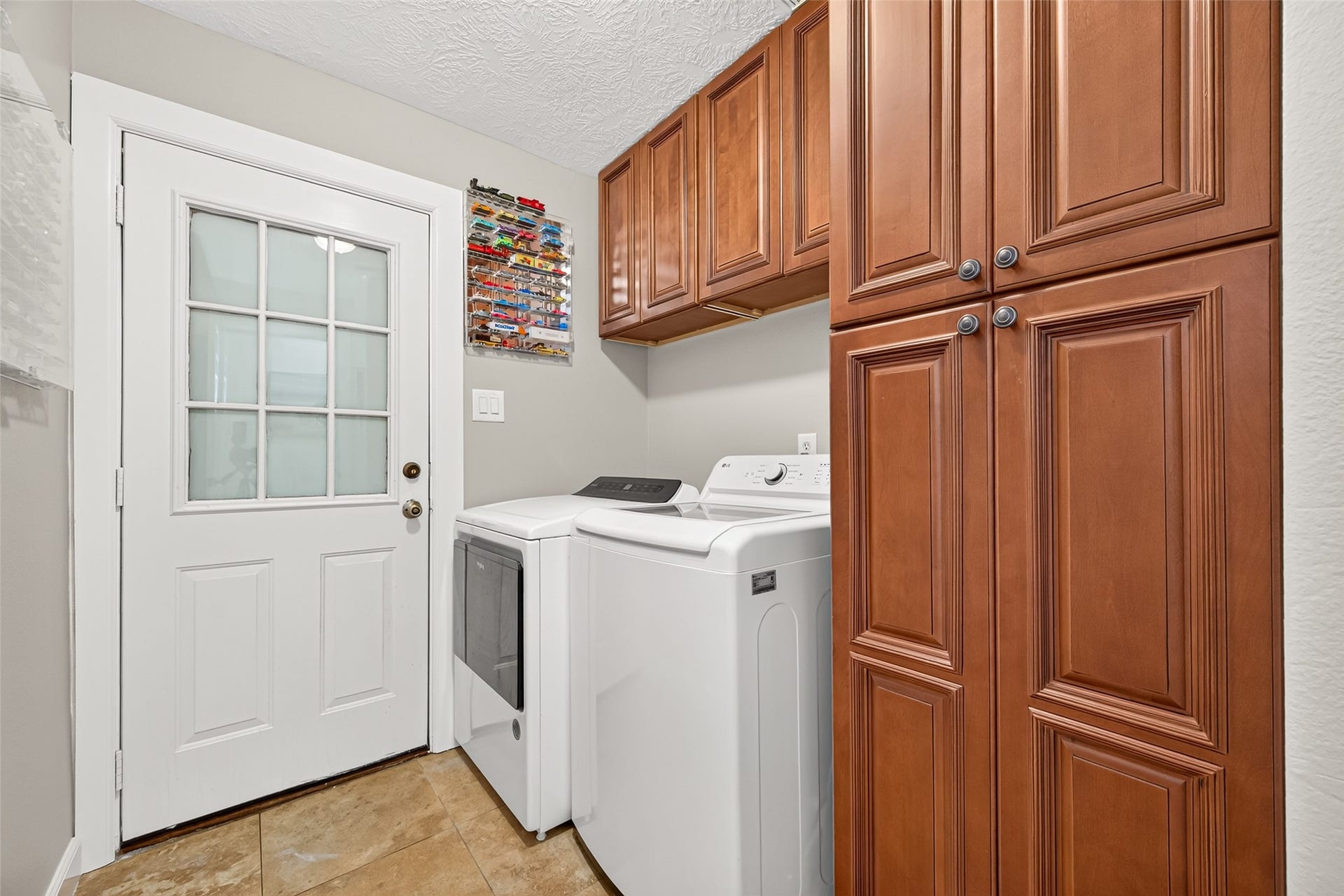 Utility room with washer and dryer space, abundant built-in cabinetry and convenient exterior access.