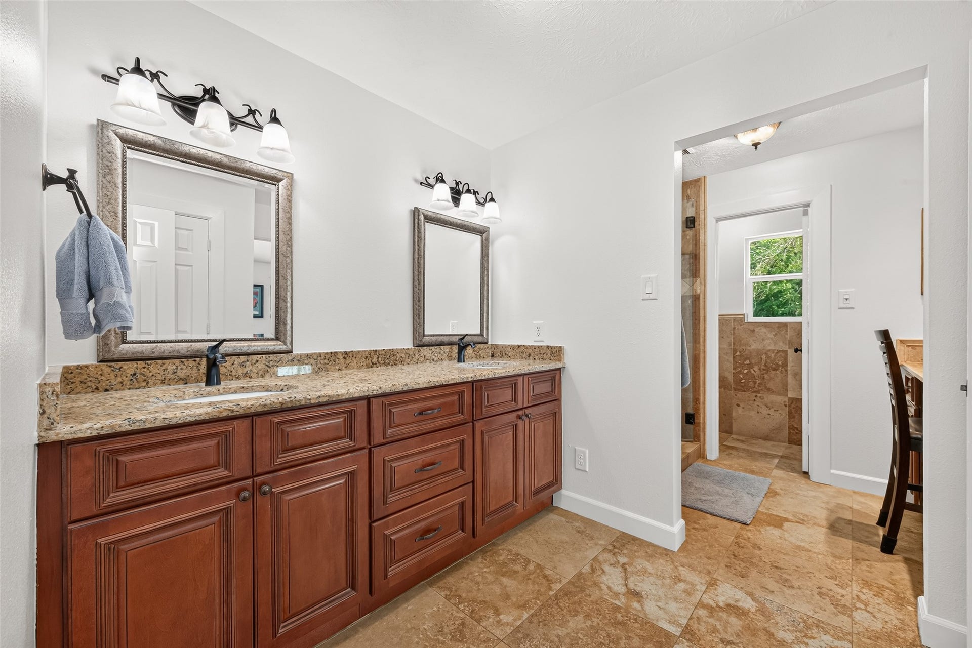Primary en-suite bath features a spacious dual-sink vanity with granite countertops and abundant cabinetry.