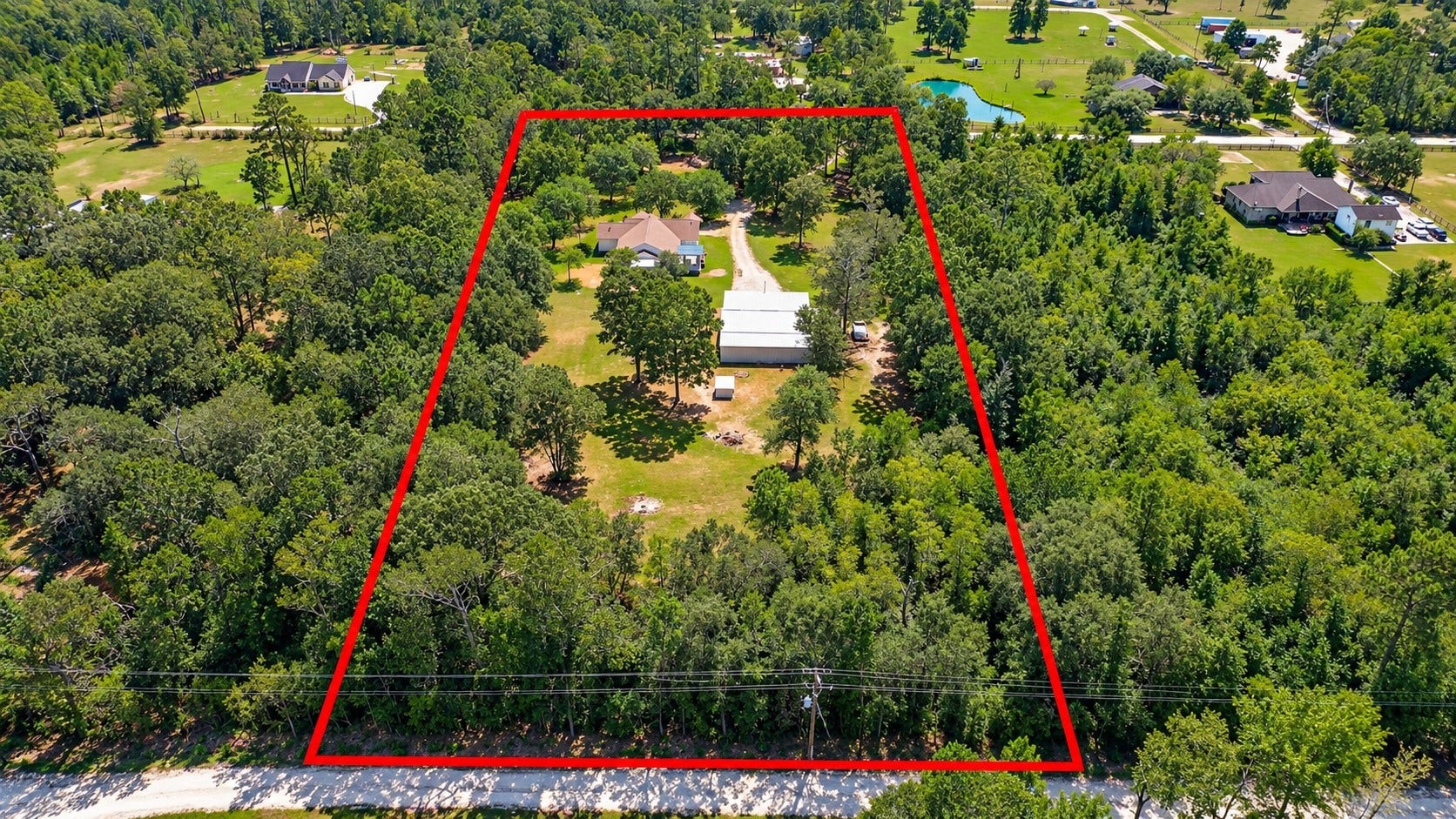Aerial view showcasing the propertys expansive acreage, mature trees, main residence, and large shop.