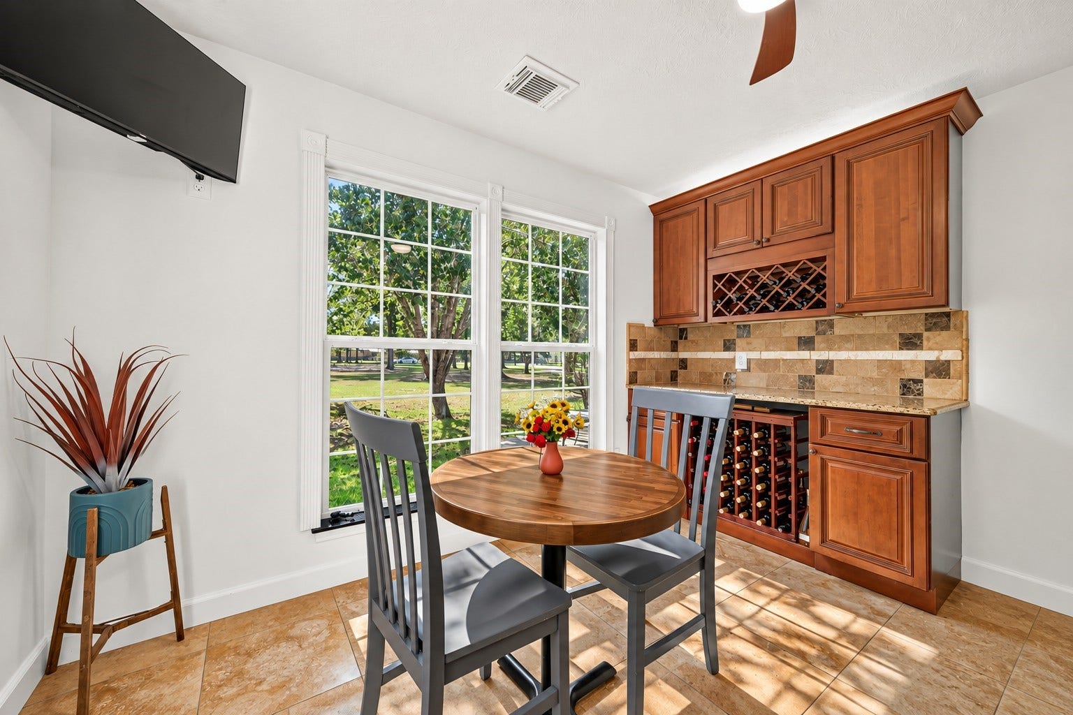 Breakfast area with built-in cabinetry, wine storage and large windows overlooking the property.