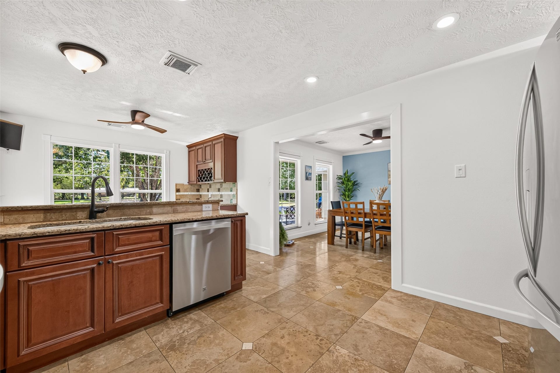 Another view of the kitchen highlighting the granite countertops, stainless steel appliances and easy flow into the dining area.