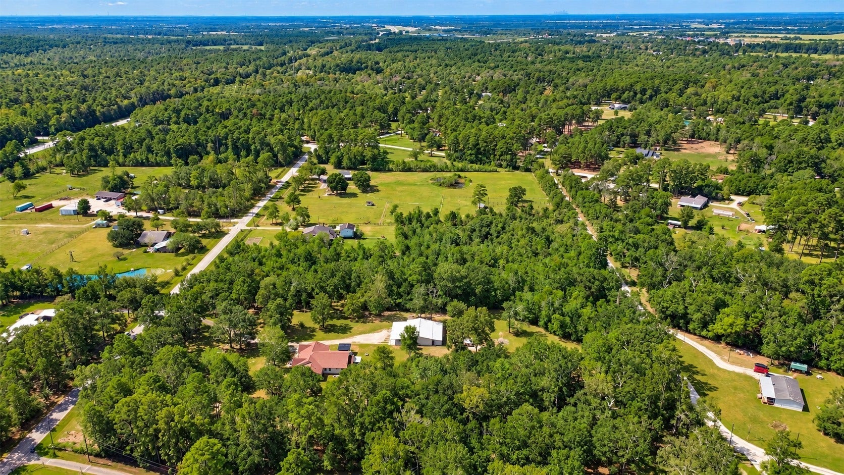 Expansive aerial view highlighting the propertys private, wooded setting with plenty of space and surrounding acreage.