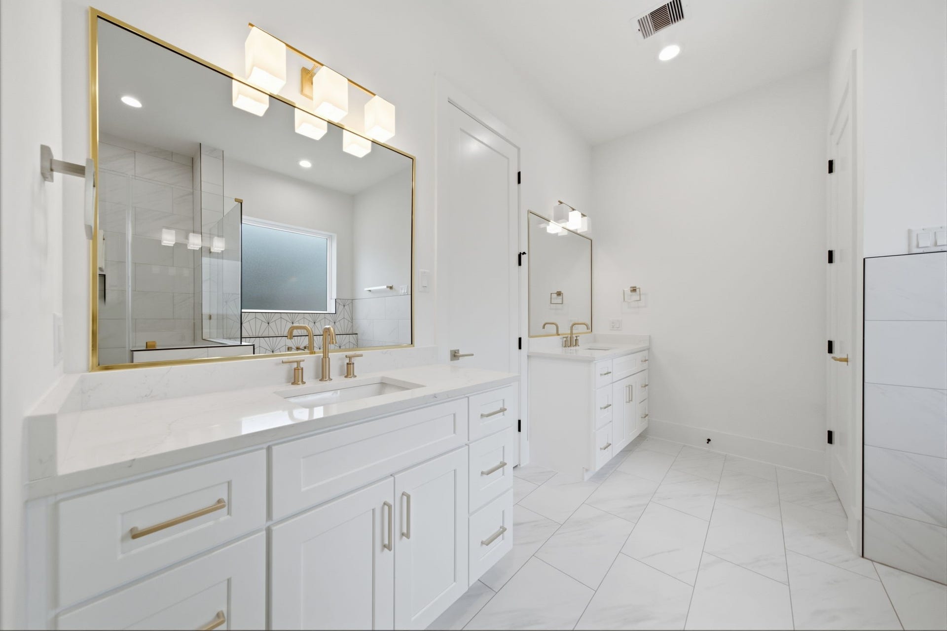Dual vanities with quartz counters, designer fixtures, and brushed brass hardware.