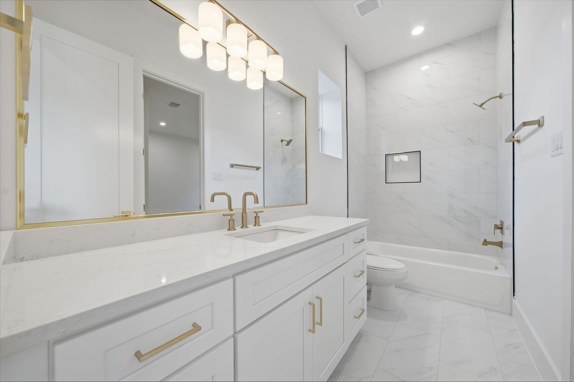 Guest bath #1 with quartz counters, brushed brass hardware, and plenty of storage and counter space.